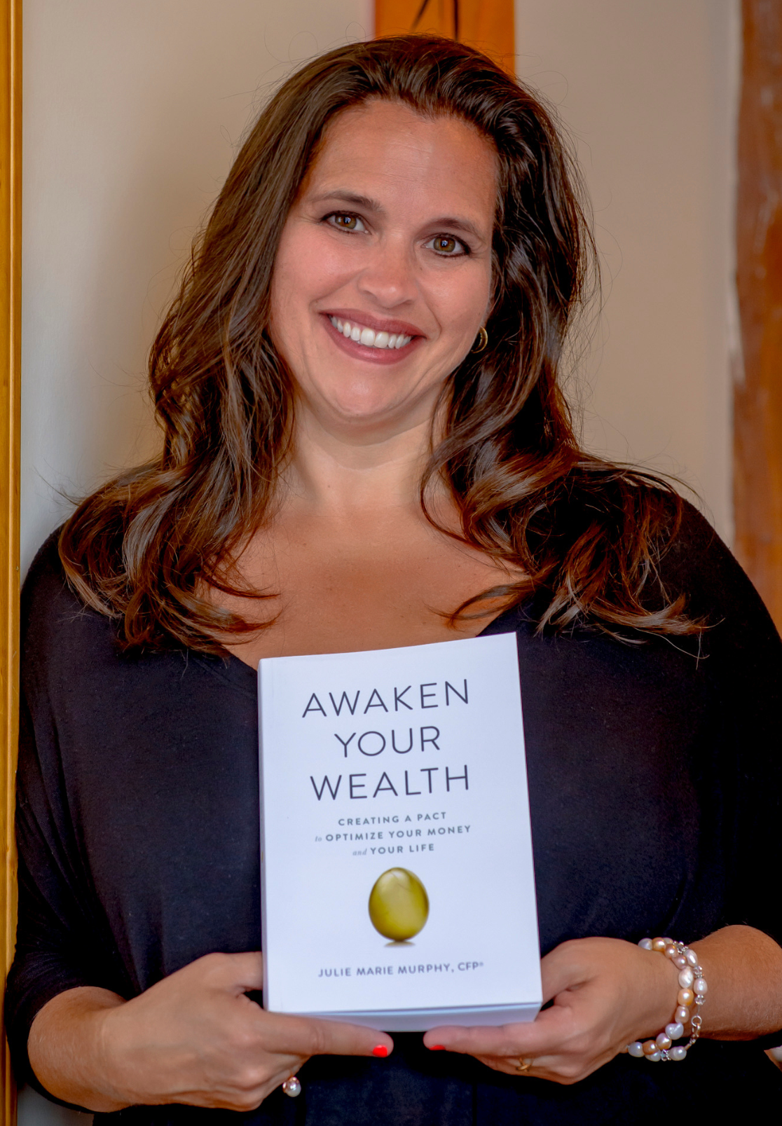 A woman is holding a book titled awaken your wealth