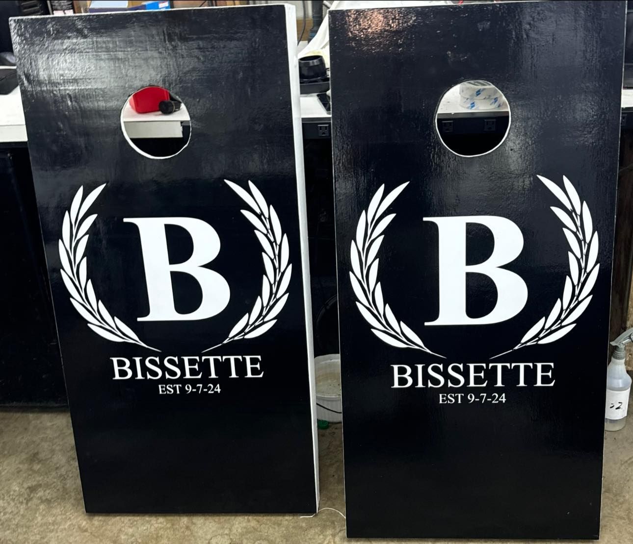 Two black cornhole boards with white 