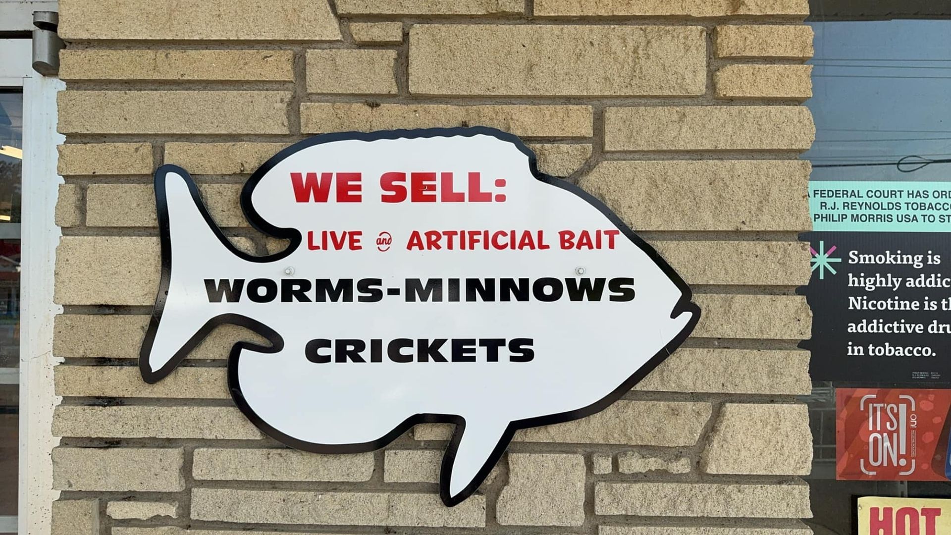 Sign in the shape of a fish, advertising live and artificial bait: worms, minnows, crickets.