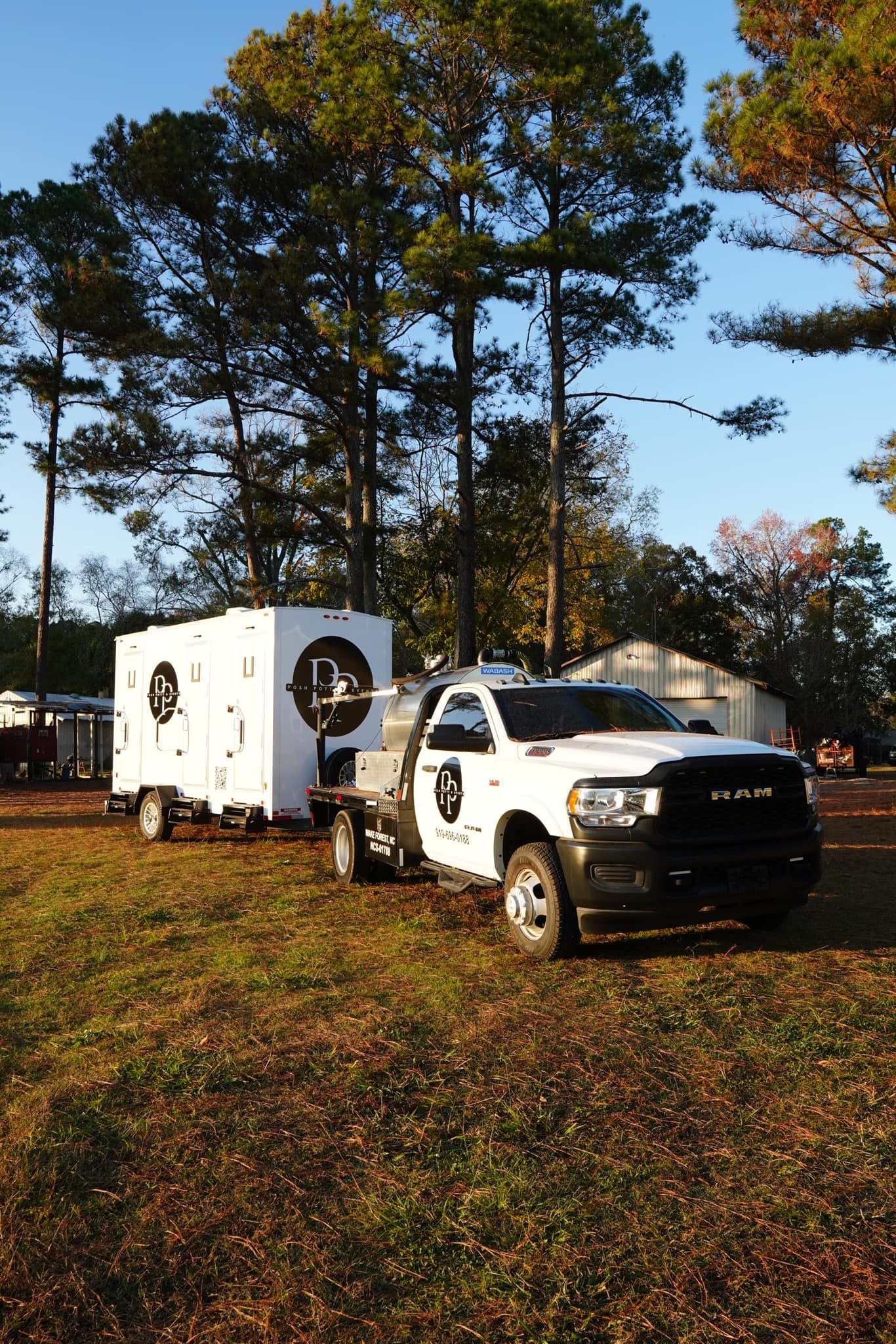White truck towing a white trailer on a grassy field with trees.