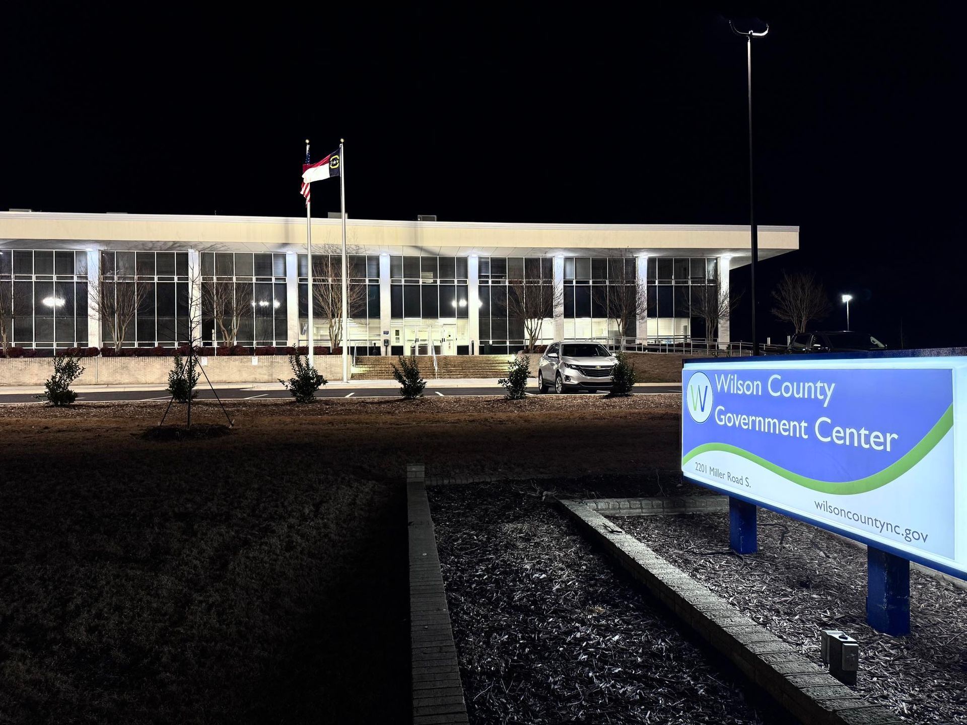 Wilson County Government Center at night, building with flag and illuminated sign.