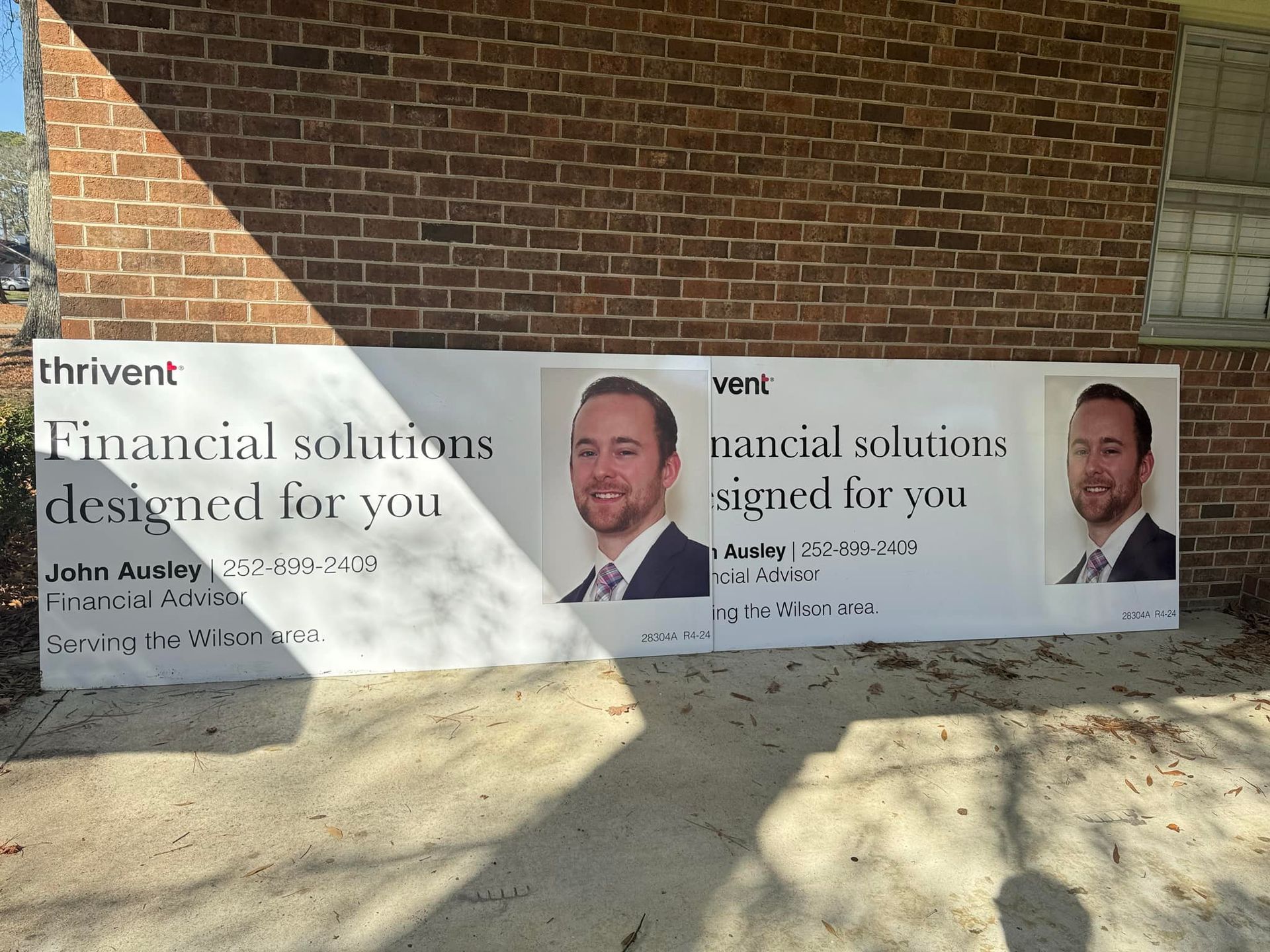 Banner advertising financial solutions, featuring a man's portrait and contact information, mounted on a brick wall.