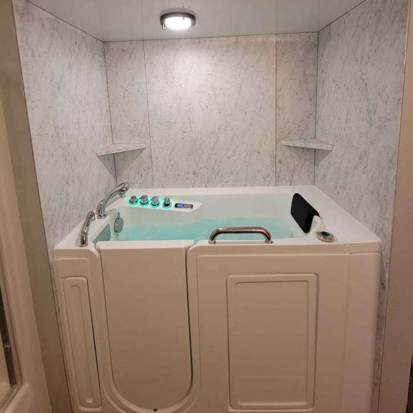 Corner bathtub with built-in seat, beige paneling, and marble-patterned walls in a small bathroom