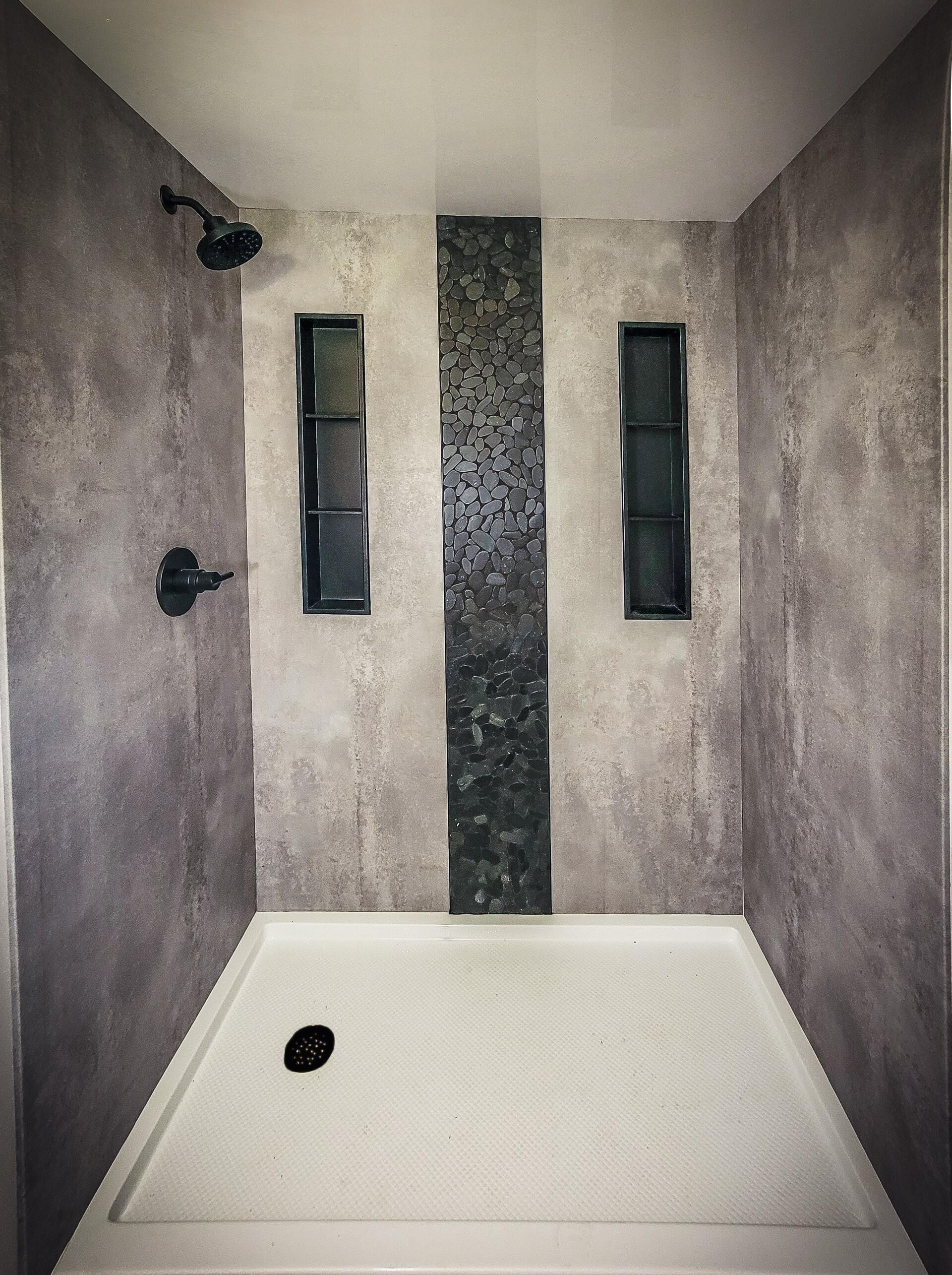 Modern shower stall with gray walls, white base, black fixtures, and narrow vertical windows