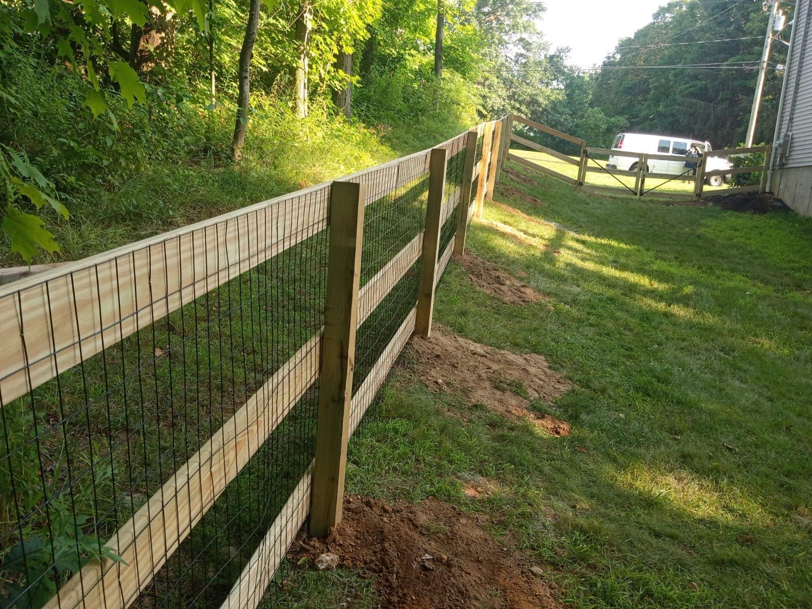 A wooden fence is surrounded by grass and trees in a yard.