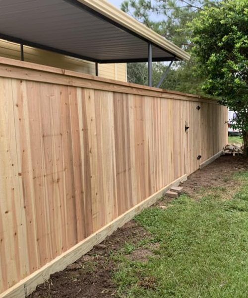 A wooden fence is being built in the backyard of a house.