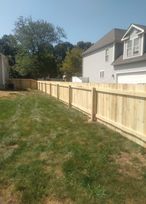 There is a wooden fence in the backyard of a house.