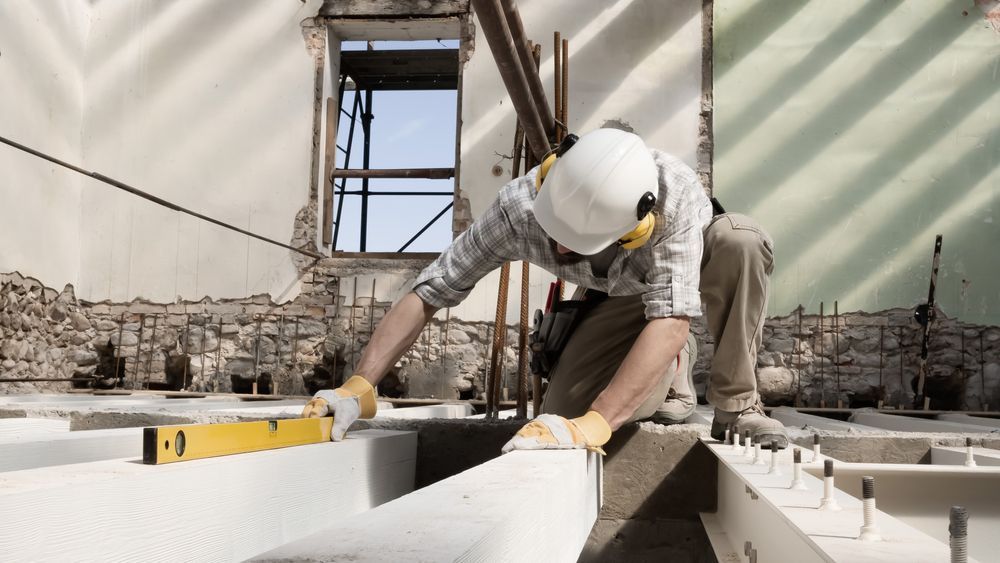 A Construction Worker Is Measuring A Piece Of Concrete With A Level — Scott Graham Building Services In Kingscliff, NSW