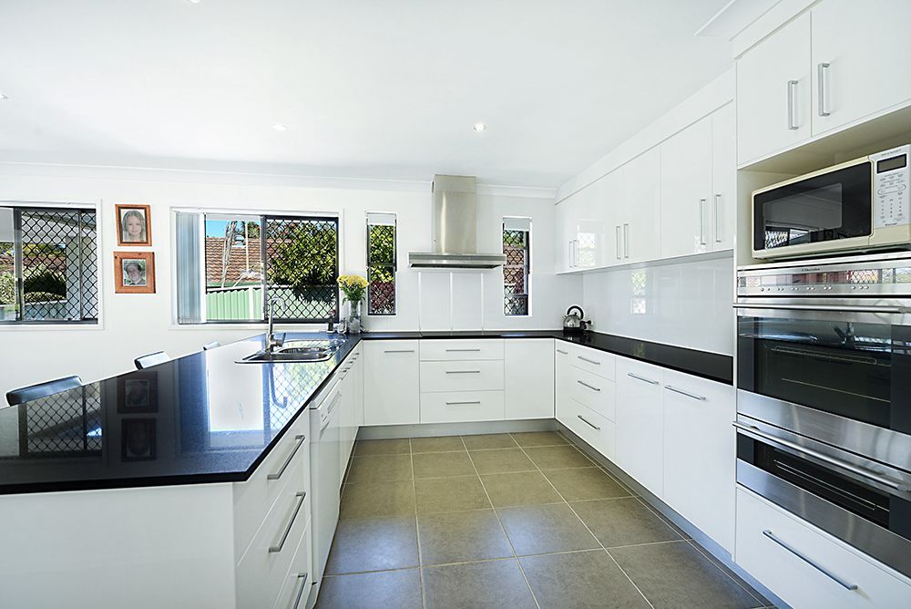 A Kitchen With White Cabinets and Black Counter Tops  — Scott Graham Building Services In Bilambil Heights, NSW 