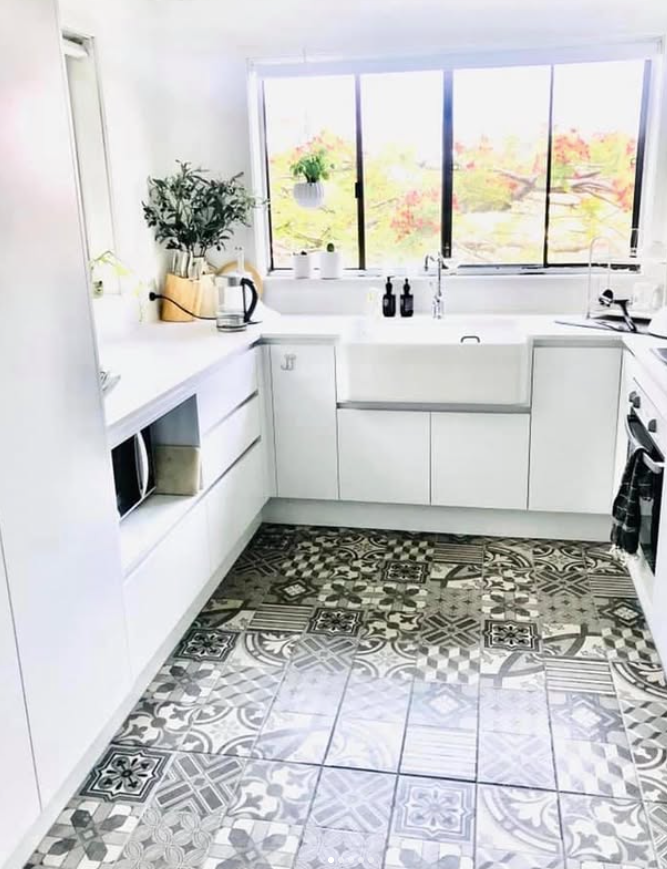 A kitchen with white cabinets and a black and white tile floor.