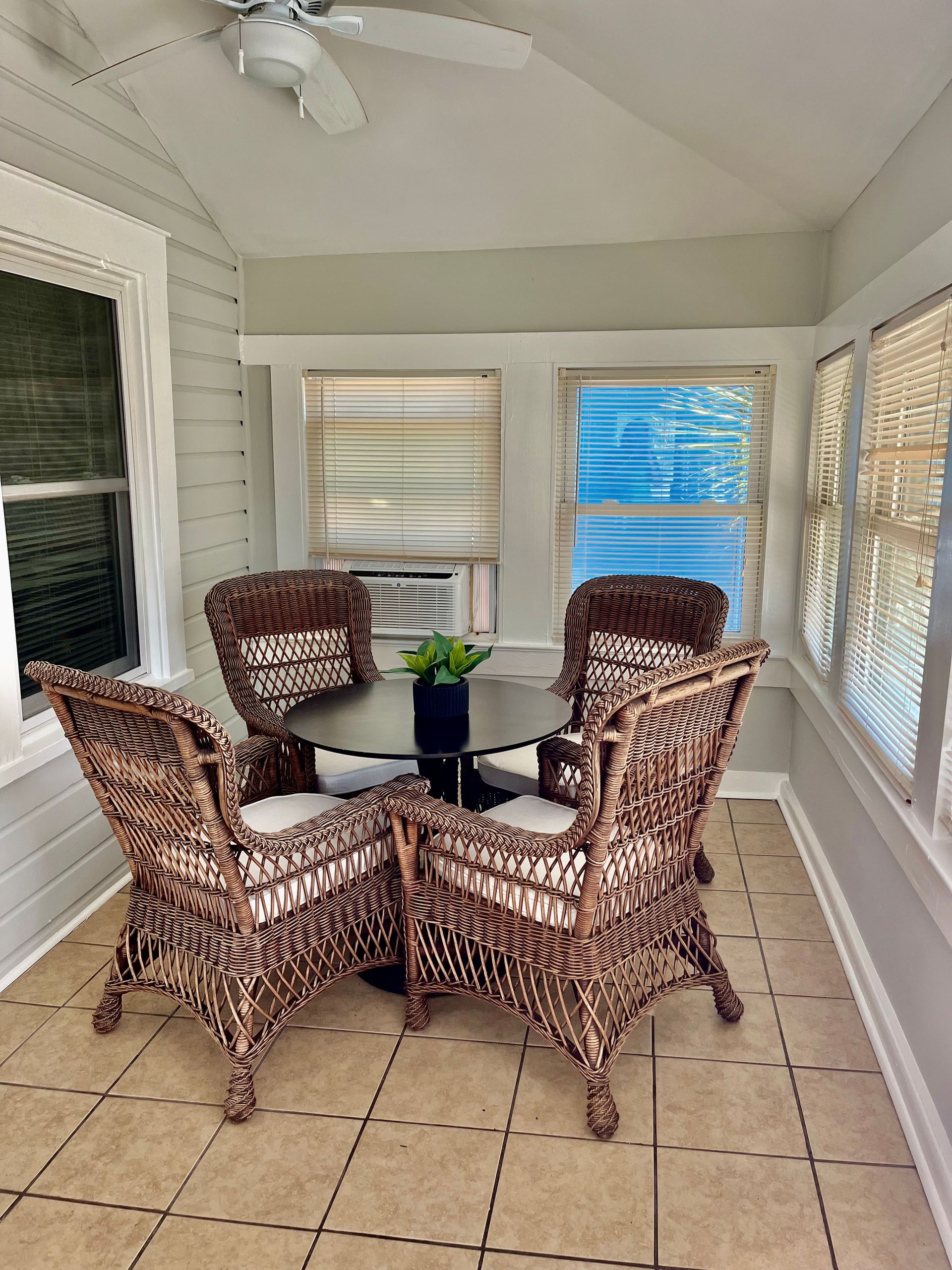 A charming sunroom at Seabirds Motel at Kure Beach with a wicker dining set, ideal for enjoying a meal or relaxing with a view. This cozy space adds to the inviting, pet-friendly atmosphere of this North Carolina lodging.