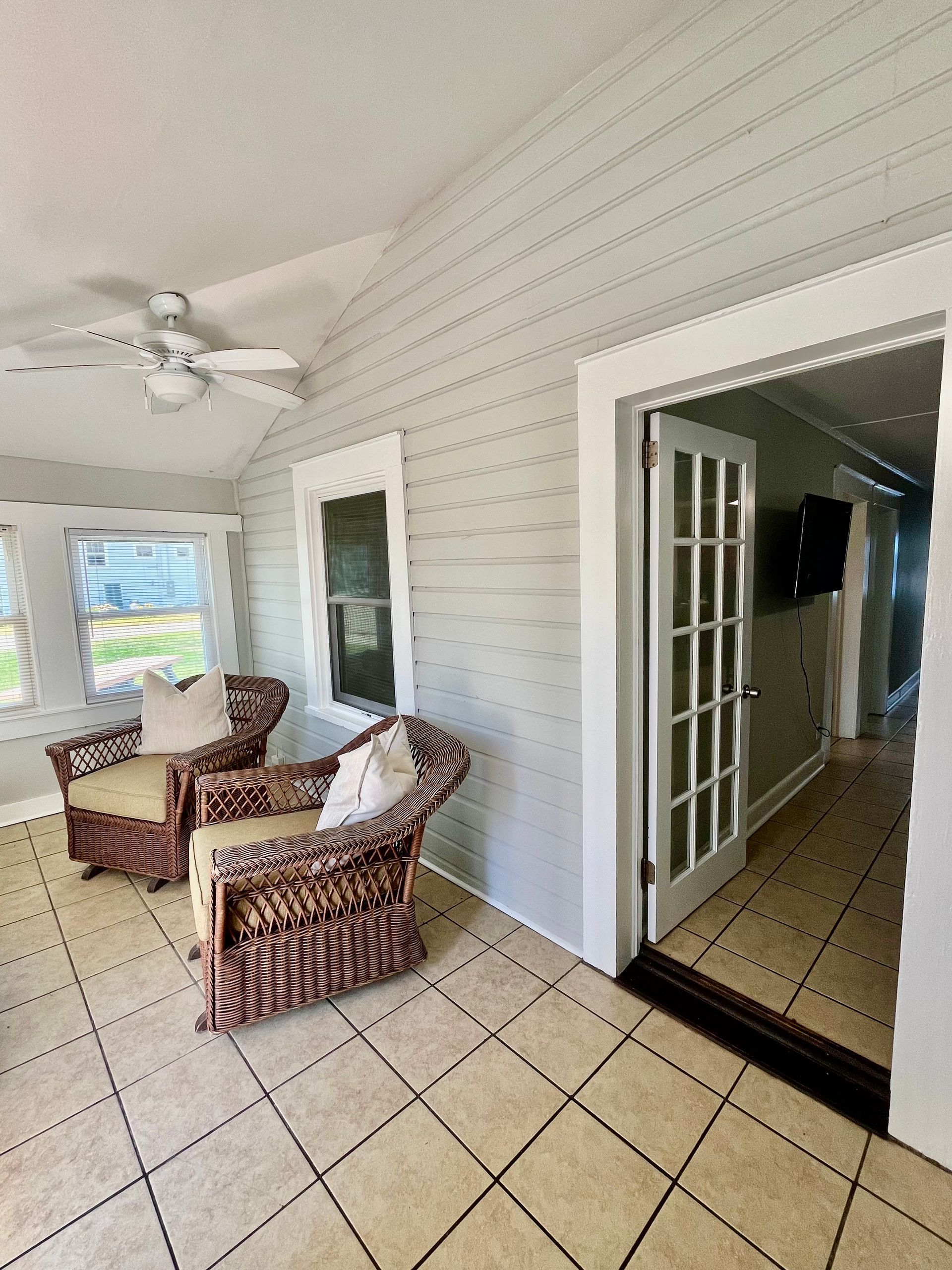 A close-up view of a sunroom at Seabirds Motel at Kure Beach featuring wicker armchairs and decorative cushions. This inviting space is perfect for lounging and enjoying natural light, reflecting the pet-friendly, comfortable atmosphere of this North Carolina lodging.