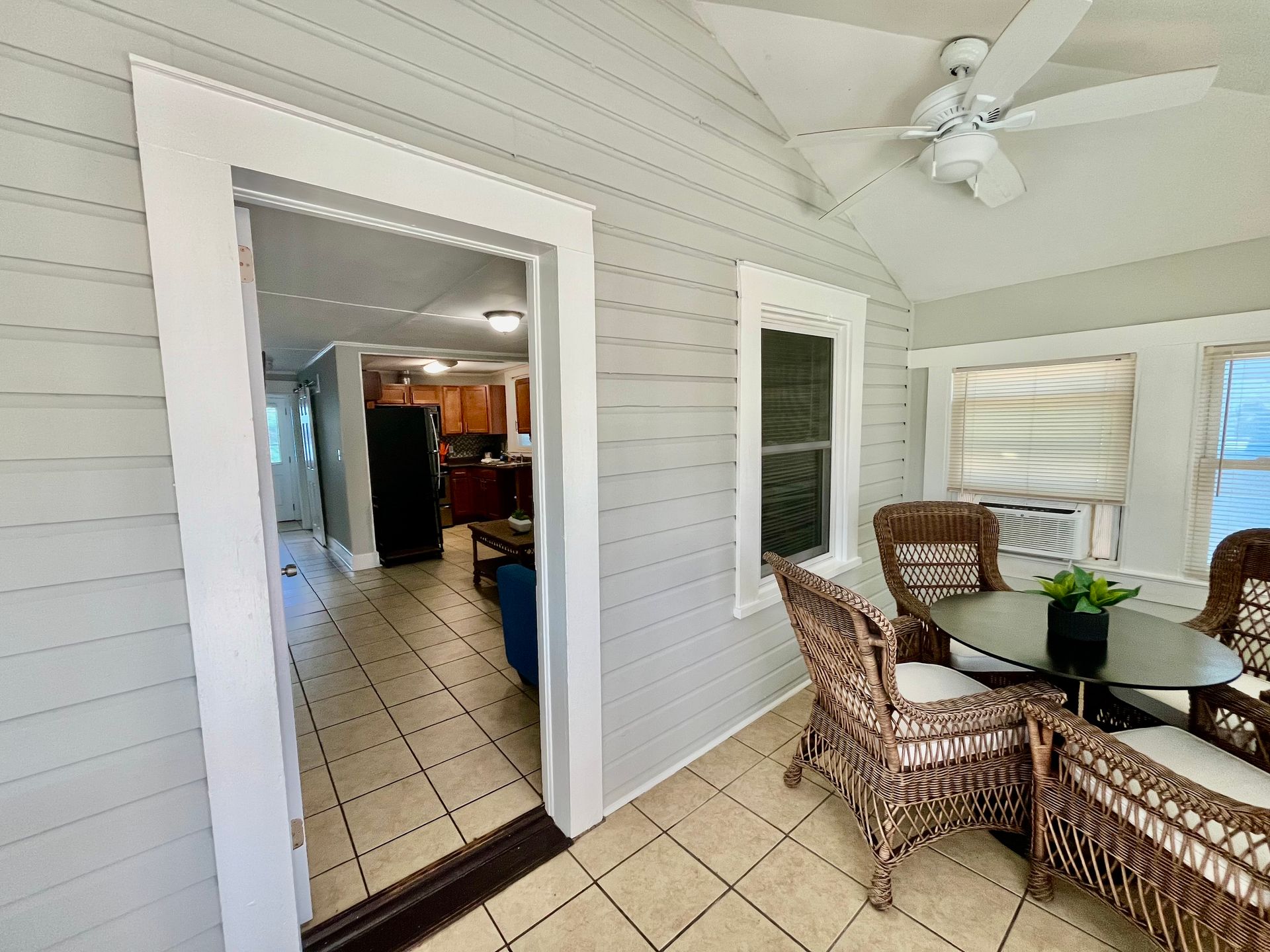 A bright sunroom at Seabirds Motel at Kure Beach with wicker furniture, including a dining table and chairs. The sunroom offers a cozy and comfortable space for guests to relax, adding to the pet-friendly charm of this North Carolina lodging.