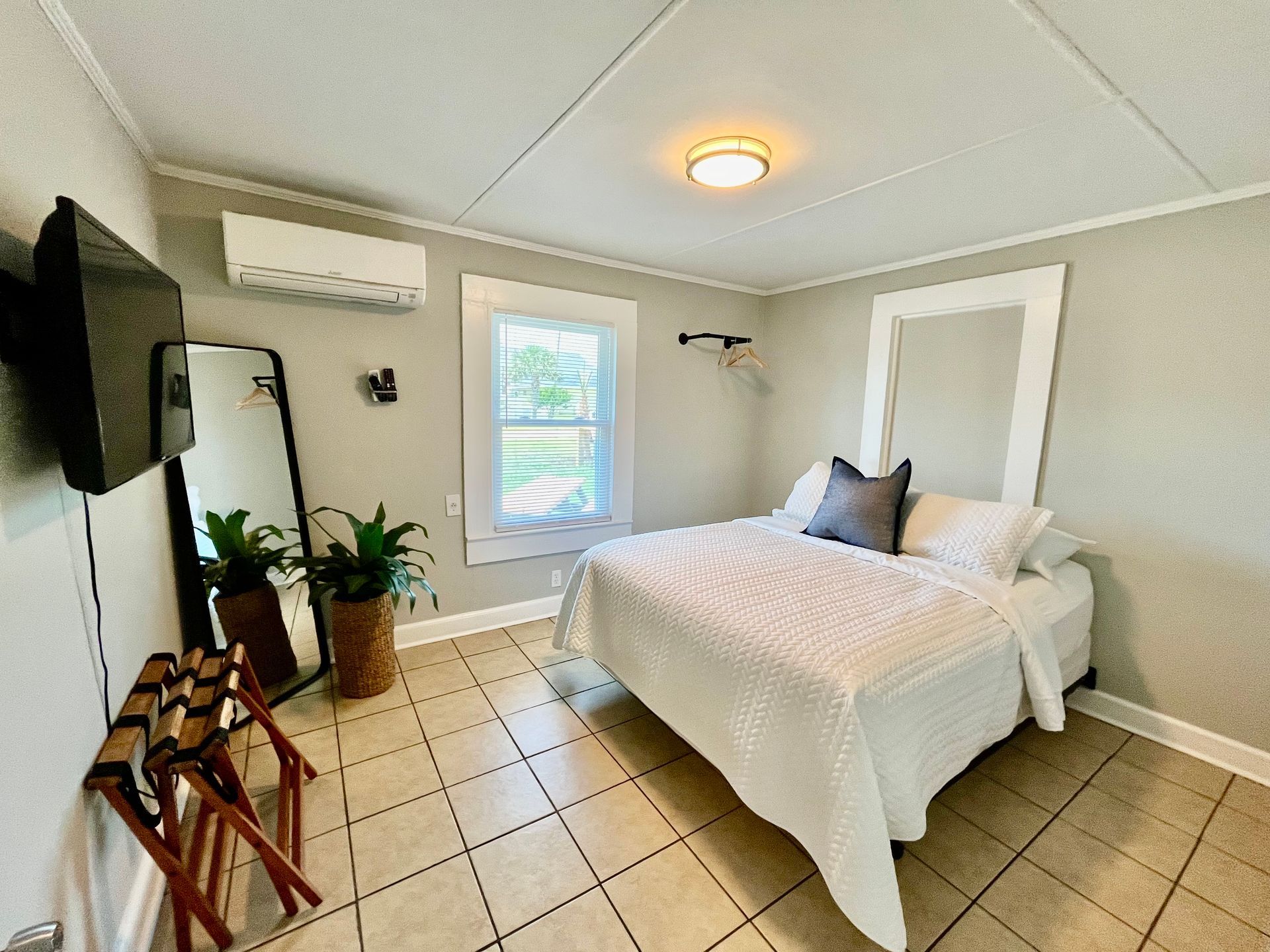 A modern guest room at Seabirds Motel at Kure Beach featuring a queen-sized bed with white bedding, a flat-screen TV, and minimalist decor. The room offers a clean and comfortable setting for guests, ideal for a pet-friendly North Carolina lodging option.