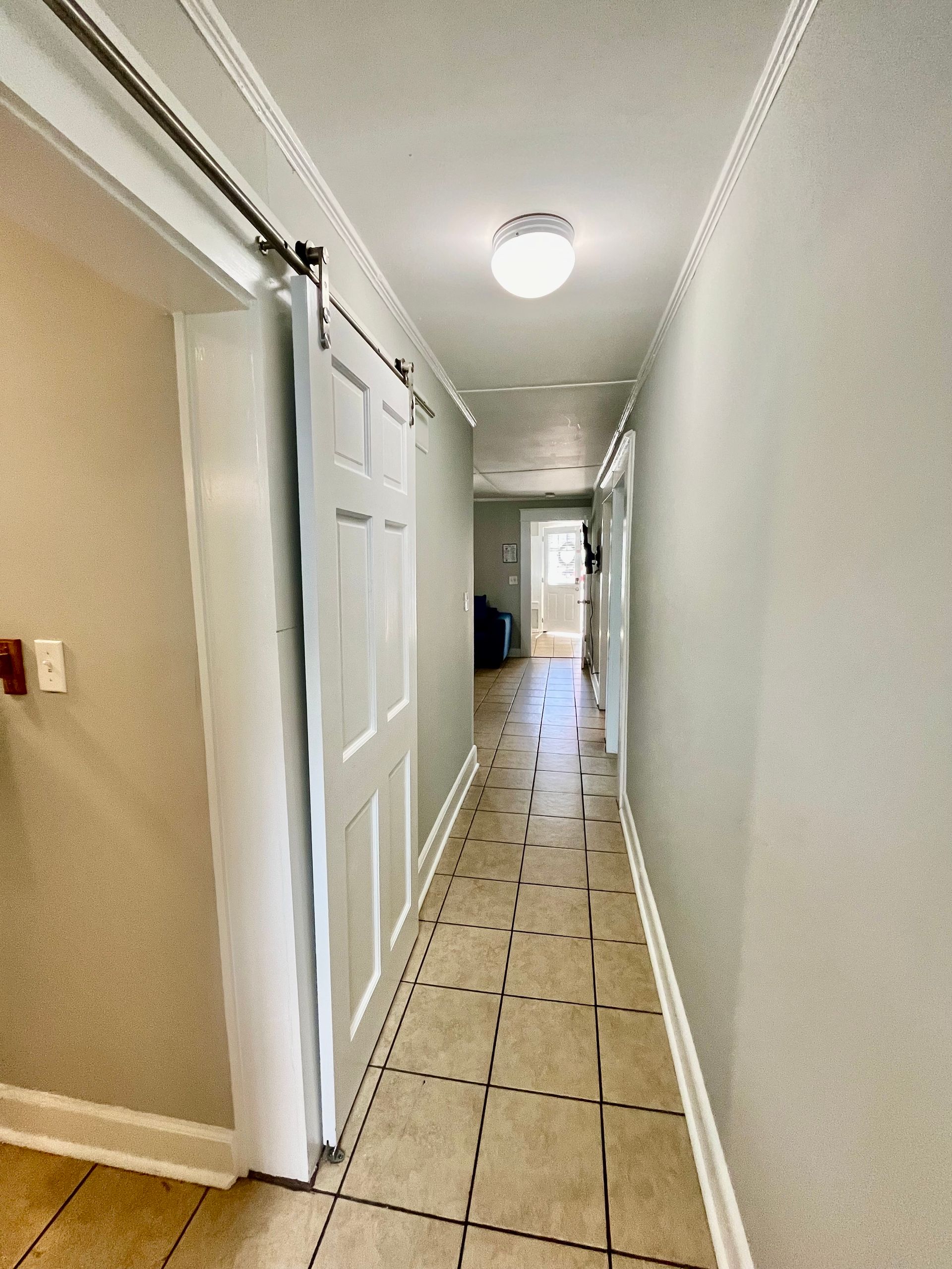 A well-lit hallway at Seabirds Motel at Kure Beach, featuring tiled flooring and a neutral color palette. The hallway connects various rooms, providing easy access throughout this pet-friendly North Carolina lodging.