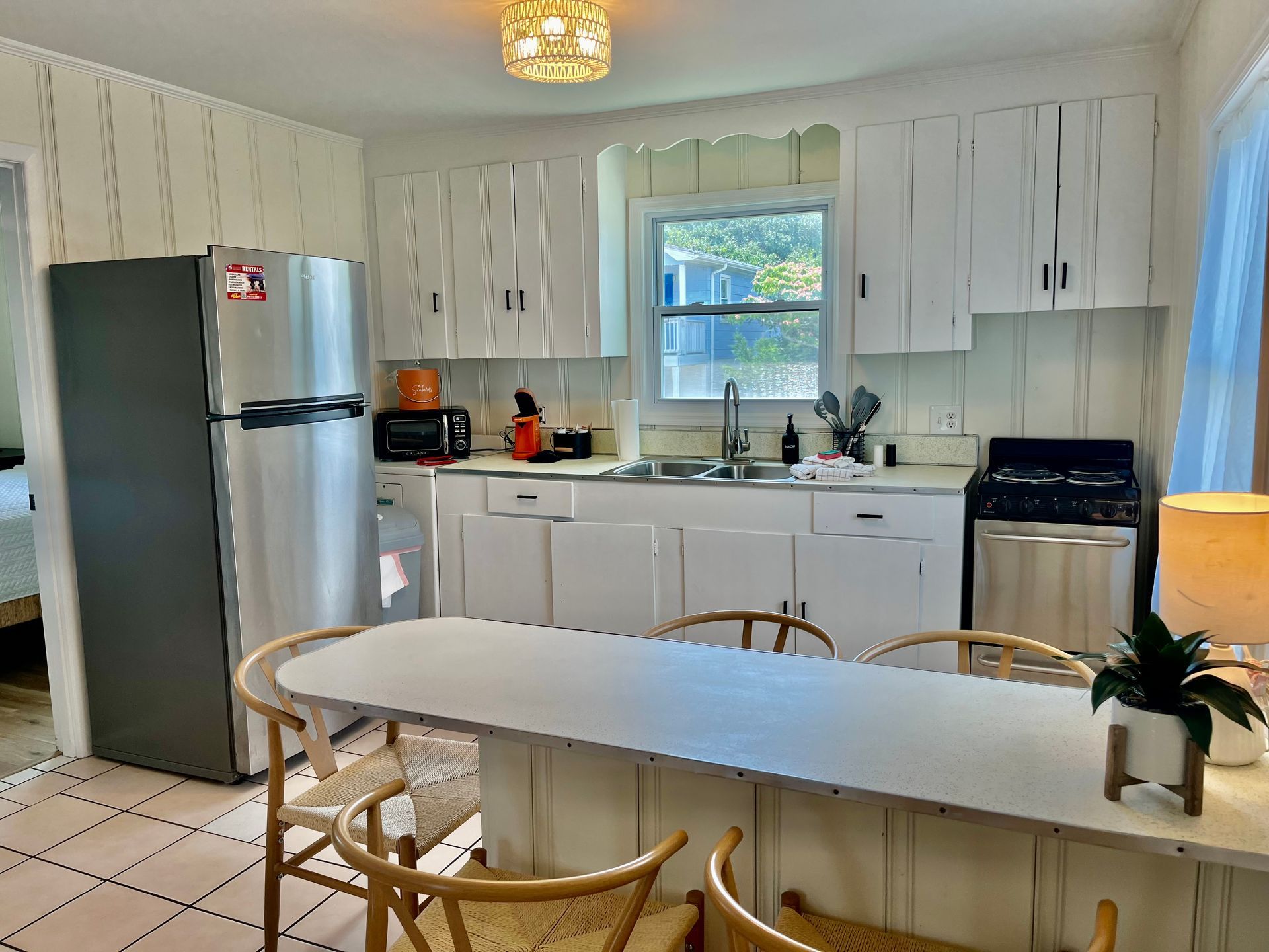 A spacious kitchen and dining area at Seabirds Motel at Kure Beach featuring a full-sized refrigerator, stove, and a large dining table. The area is perfect for family gatherings or group stays in this pet-friendly North Carolina lodging.