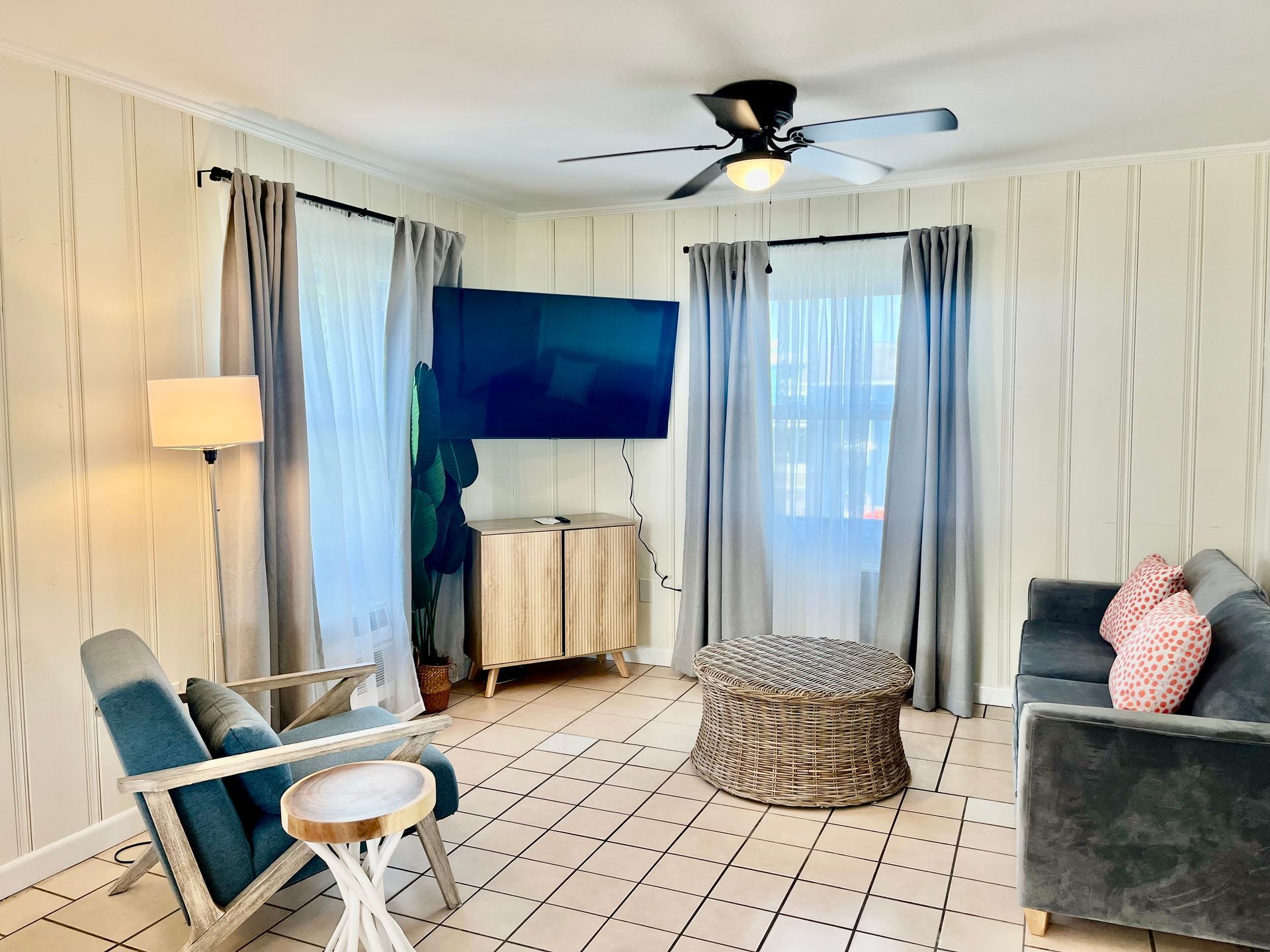  A spacious living area at Seabirds Motel at Kure Beach featuring a large flat-screen TV, blue armchairs, and coastal decor. This room offers a comfortable setting for a pet-friendly stay in North Carolina.