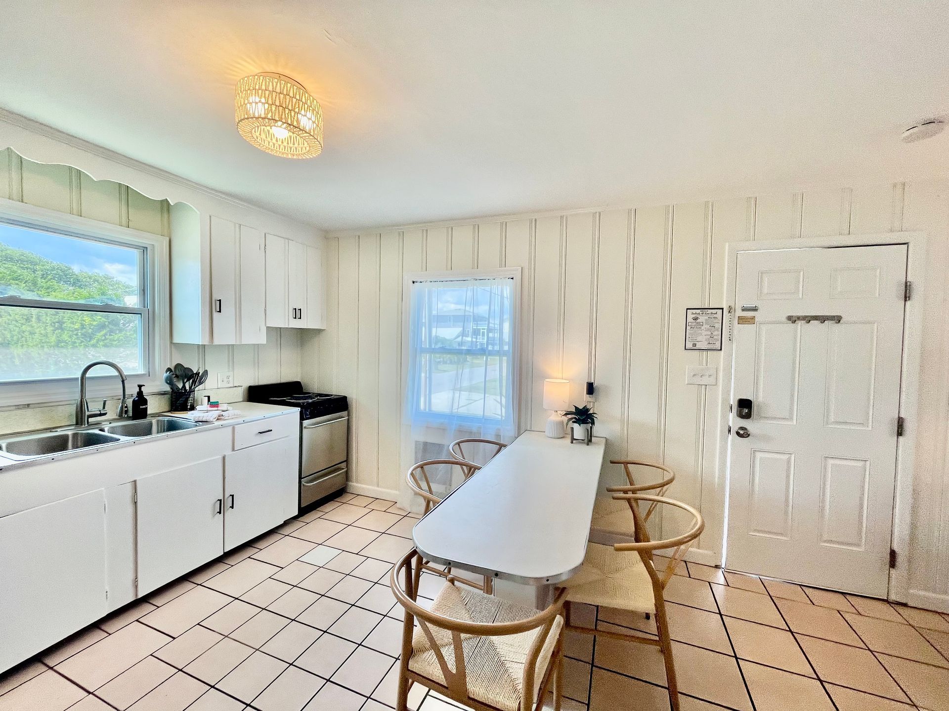 A bright kitchen and dining area at Seabirds Motel at Kure Beach with a full-sized refrigerator, stove, and dining table. The room is perfect for guests who enjoy cooking their own meals, offering a pet-friendly lodging experience in North Carolina.
