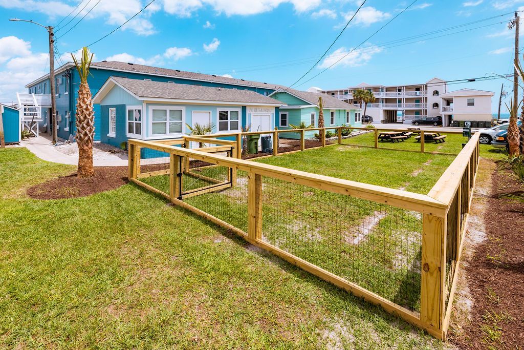 Another view of the fenced-in pet play area at Seabirds Motel at Kure Beach, showcasing a large, grassy space surrounded by wooden fencing. This outdoor area emphasizes the motel's dedication to providing a safe and enjoyable environment for pets and their owners, supporting a pet-friendly North Carolina lodging.