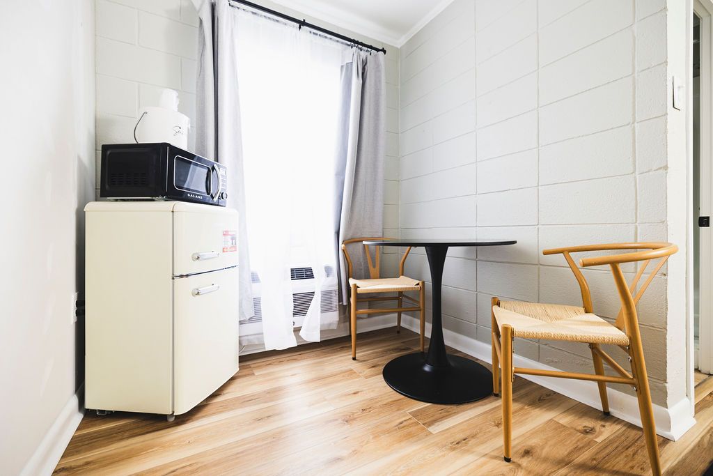 A cozy room at Seabirds Motel at Kure Beach featuring a small dining area with chairs, a retro mini-fridge, and a microwave. The room is designed for comfort and convenience, perfect for a pet-friendly stay in North Carolina.