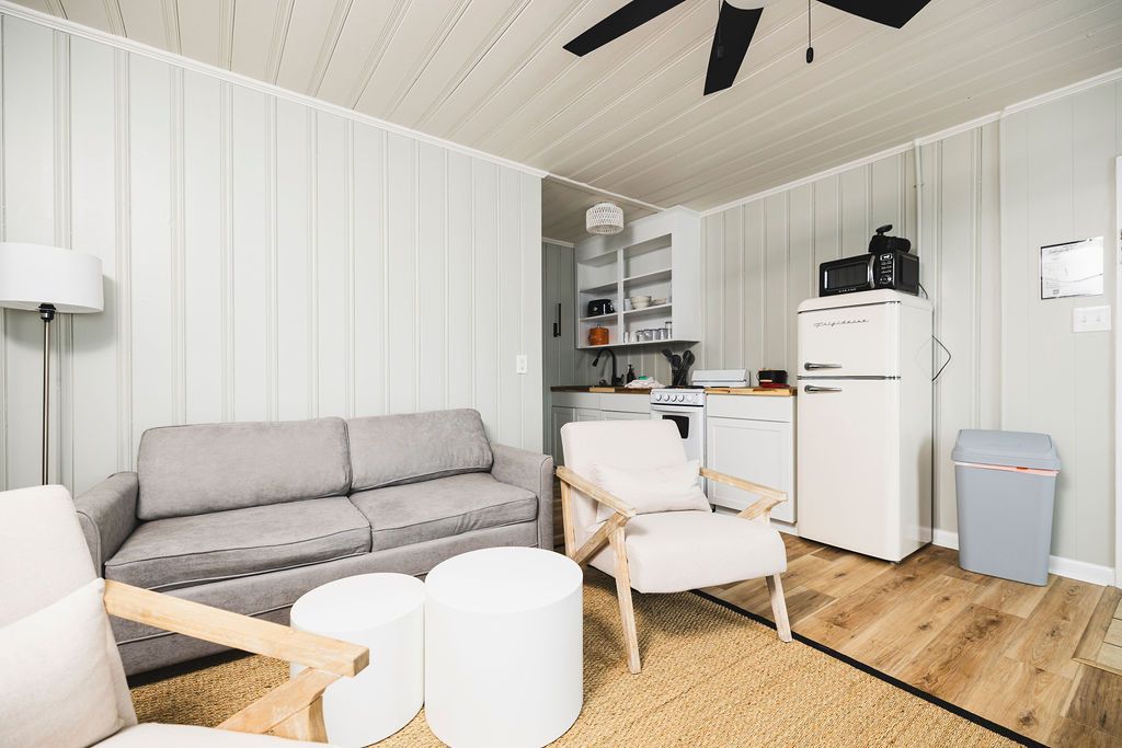 A cozy living area at Seabirds Motel at Kure Beach featuring a comfortable gray sofa, a small dining table with chairs, and a kitchenette equipped with a retro-style refrigerator and microwave. This pet-friendly North Carolina lodging offers a welcoming atmosphere for guests.