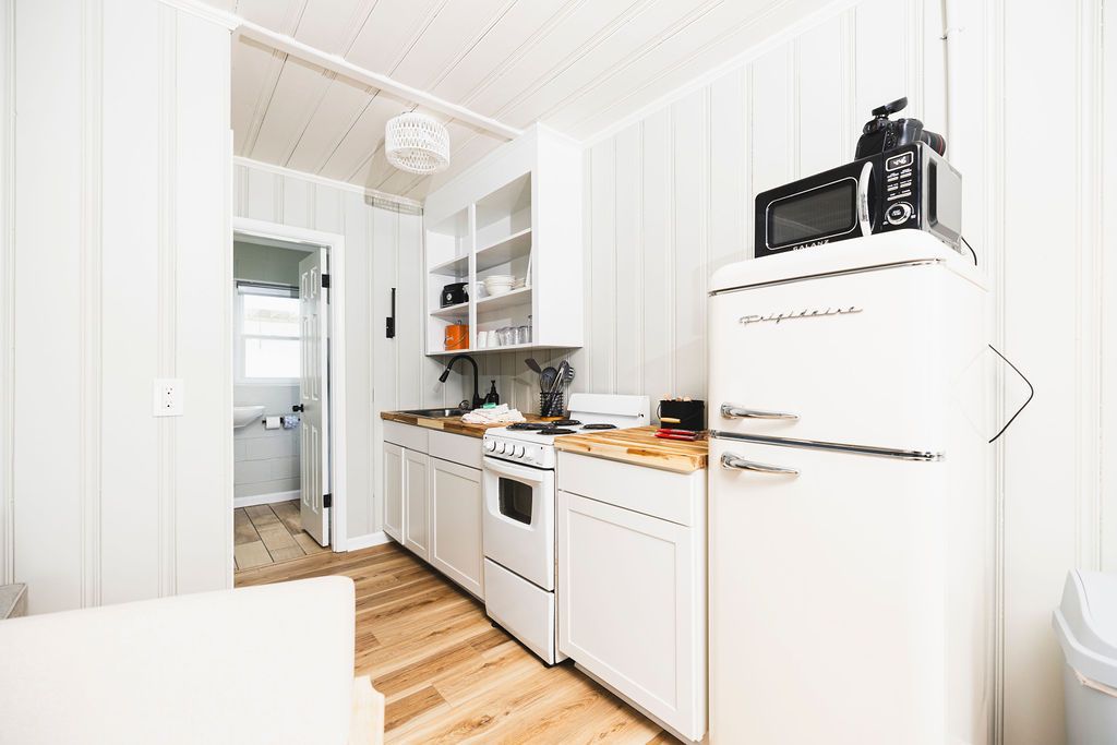 A bright and fully equipped kitchenette at Seabirds Motel at Kure Beach with a retro refrigerator, microwave, sink, and ample cabinet space. This kitchen area is ideal for guests looking to prepare their own meals during their stay at this pet-friendly North Carolina lodging.