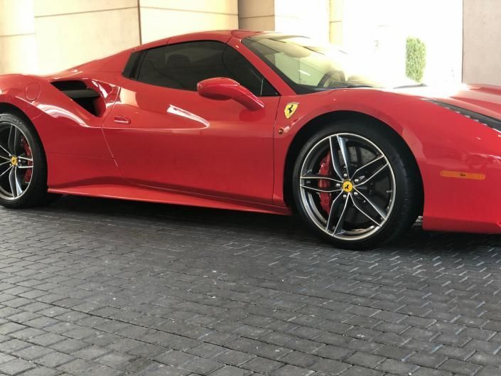Red Ferrari sports car parked in a garage, side view on a cobblestone floor