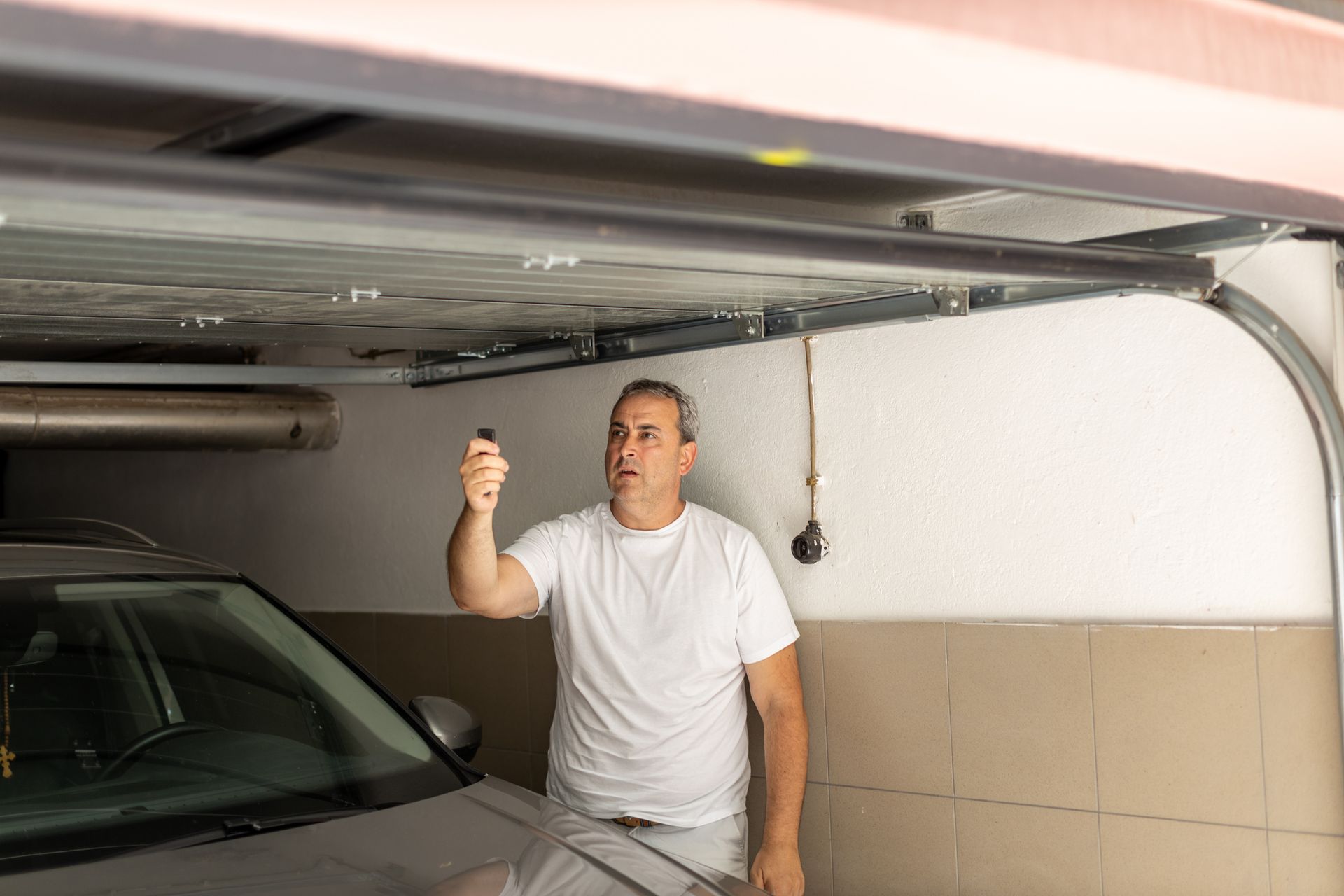 A man is standing in a garage holding a remote control.