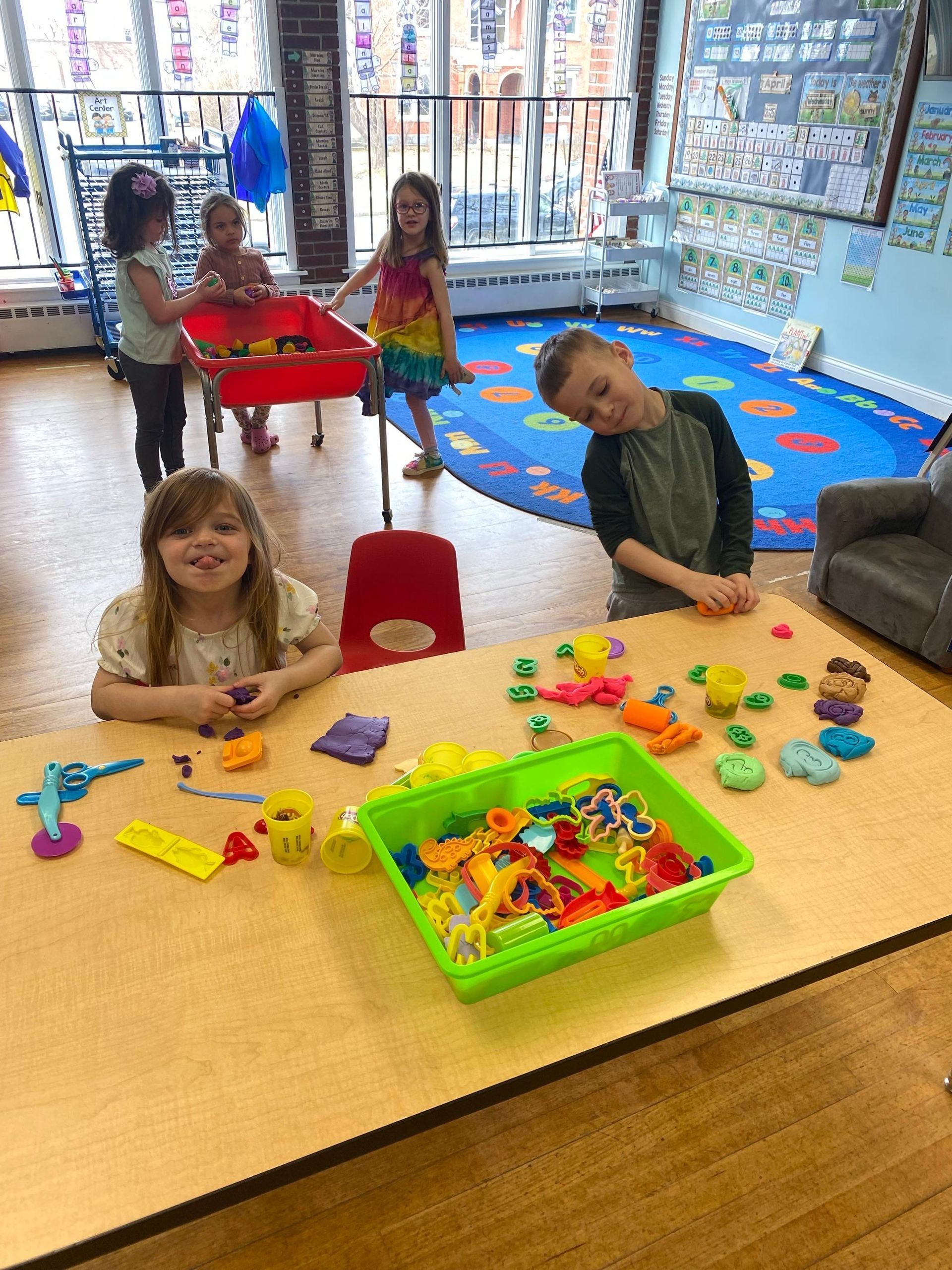 A group of children are sitting at a table playing with toys.