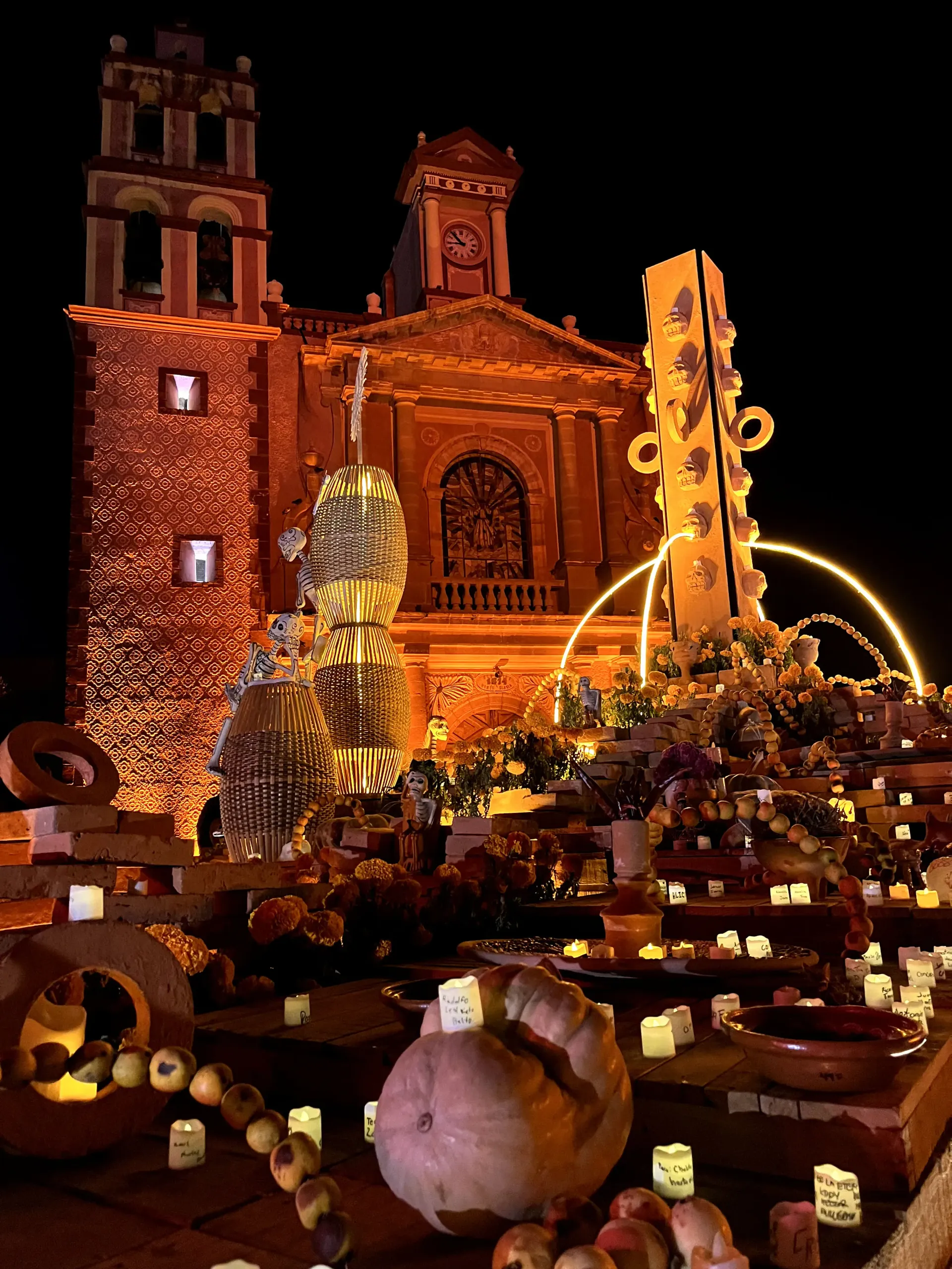 Fachada de la iglesia iluminada con una exhibición de la cosecha de otoño y calabazas iluminadas por la noche.