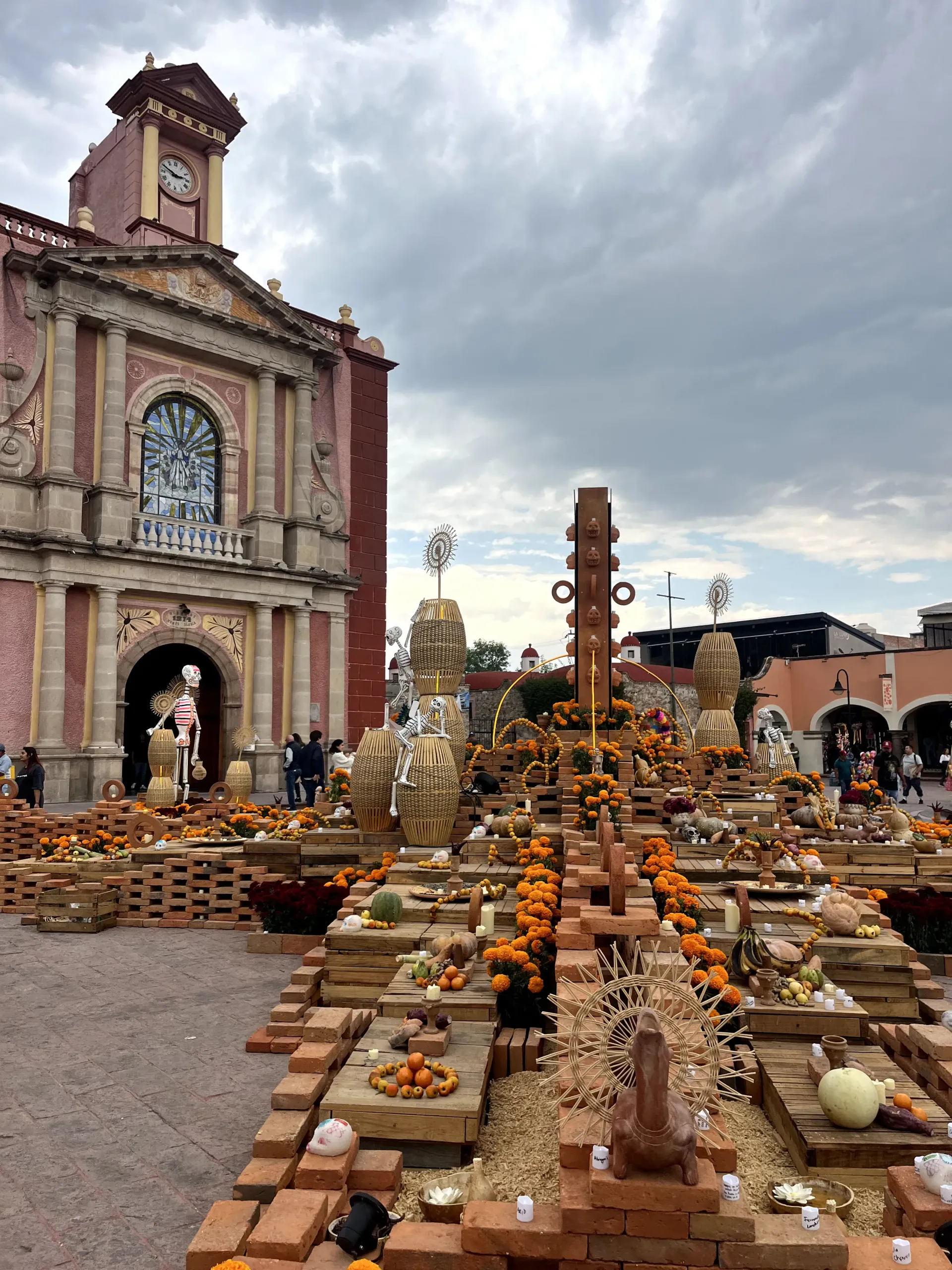 Outdoor altar of candles and flowers before a church facade under a cloudy sky