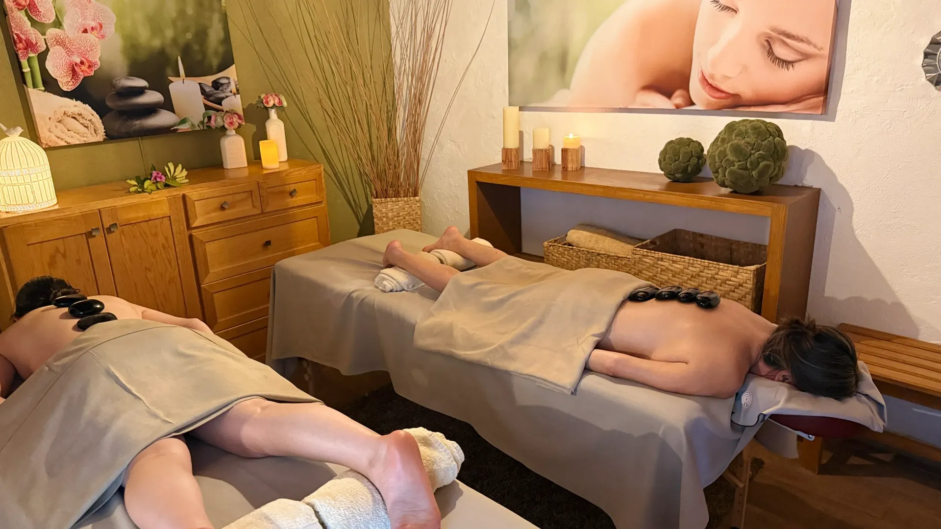 Spa room with two people lying on treatment tables during a massage session