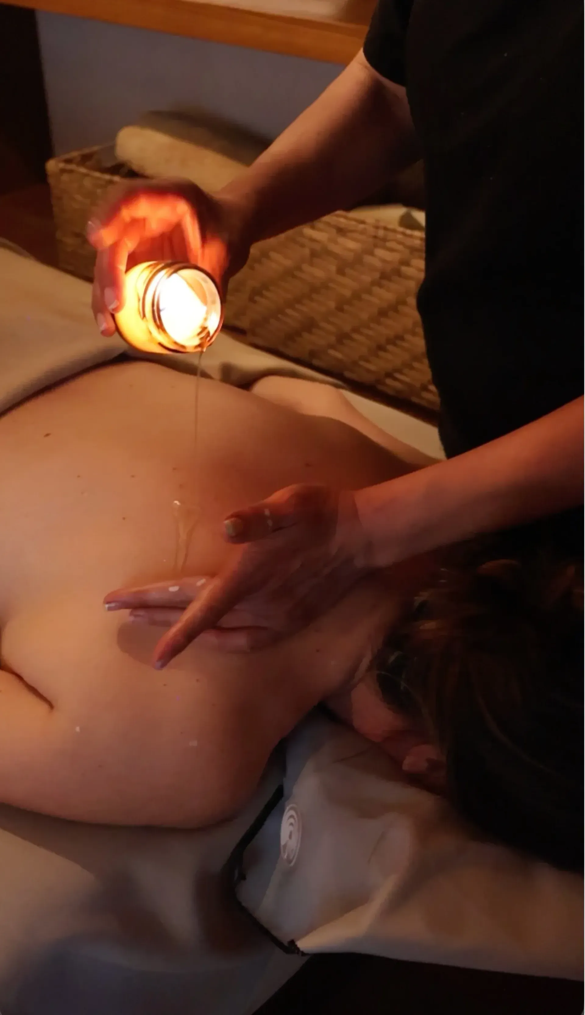 Massage therapist using a heated cup on a client's bare back during a spa treatment