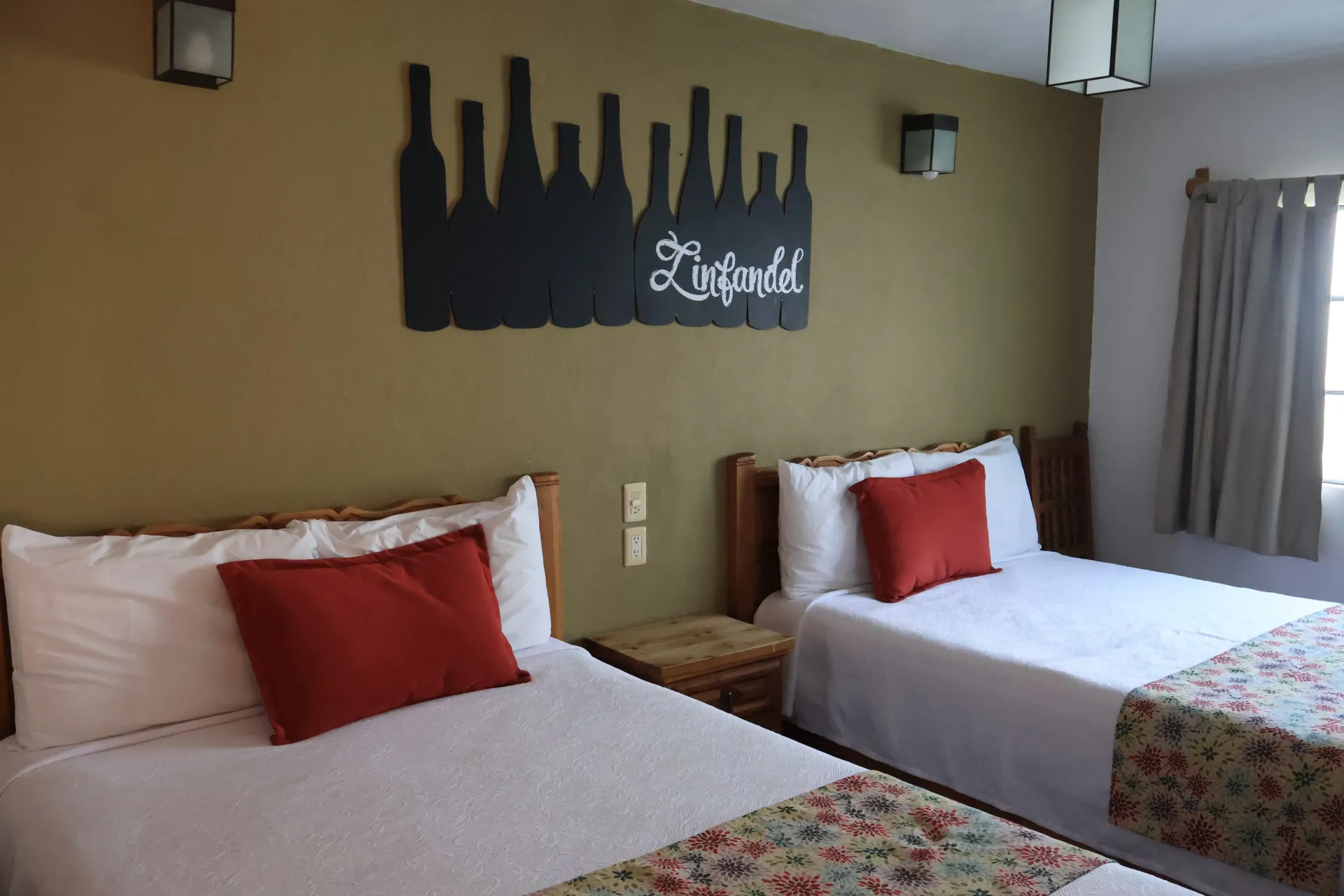 Dos camas individuales bien hechas en una habitación de hotel de color beige con un cartel en la pared y cortinas.