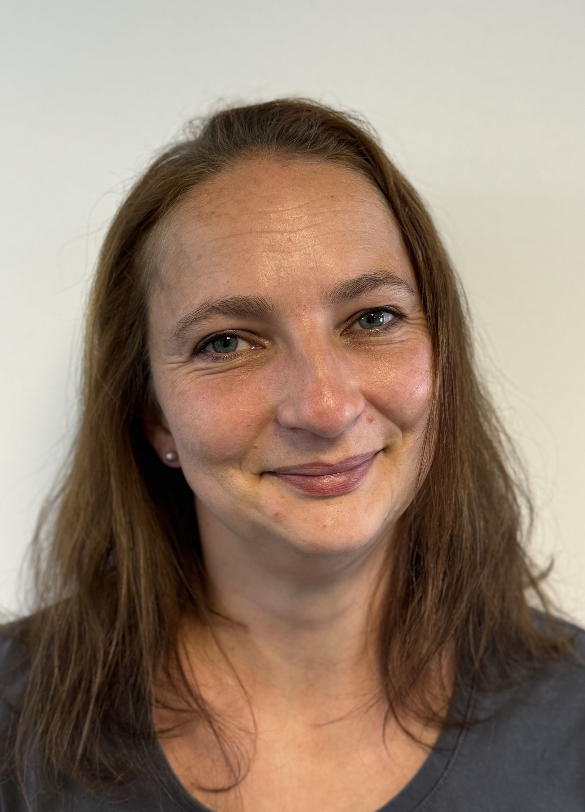 Eine Frau mit langen braunen Haaren lächelt in die Kamera.