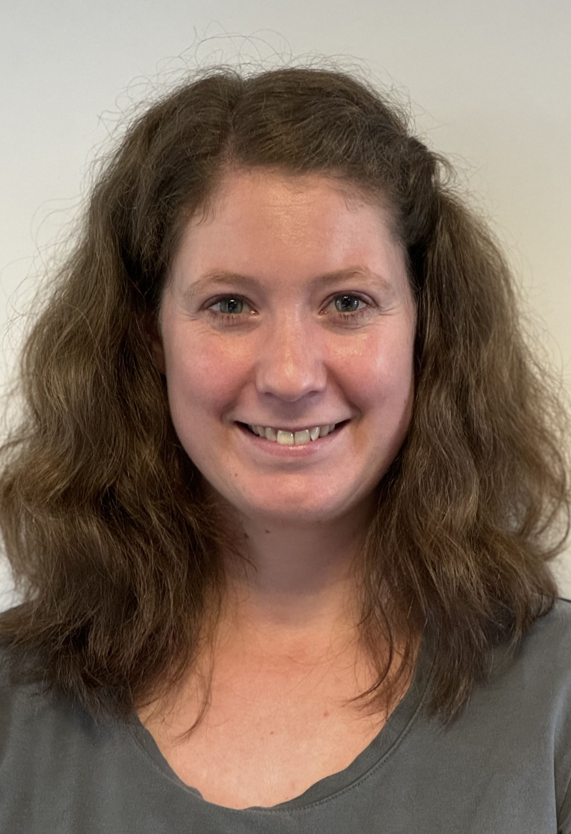 Eine Frau mit langen braunen Haaren lächelt in die Kamera.