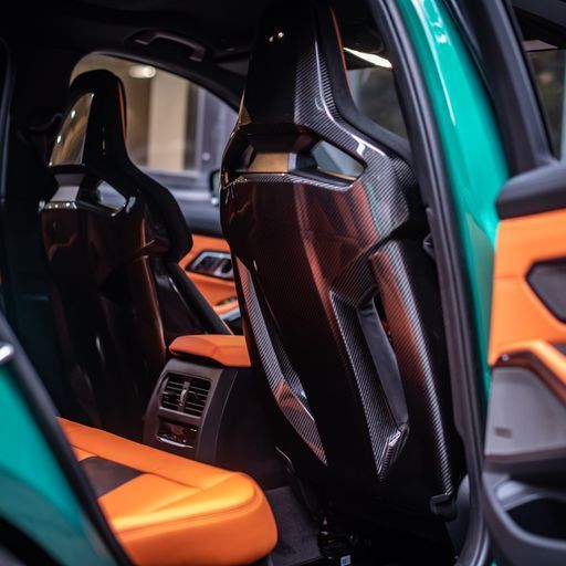 Carbon fiber car seats with orange and black leather interior.