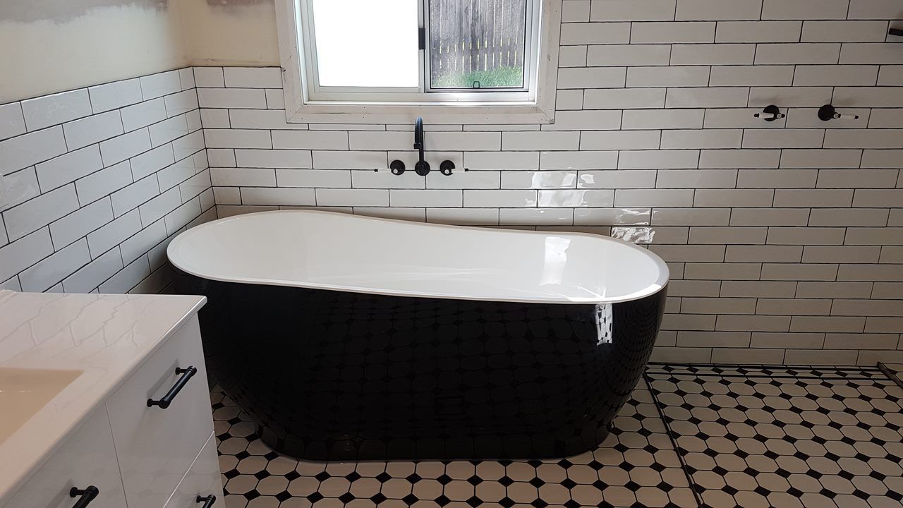 A Black And White Bathtub In A Bathroom Next To A Window — Damn Fine Constructions In Toormina, NSW