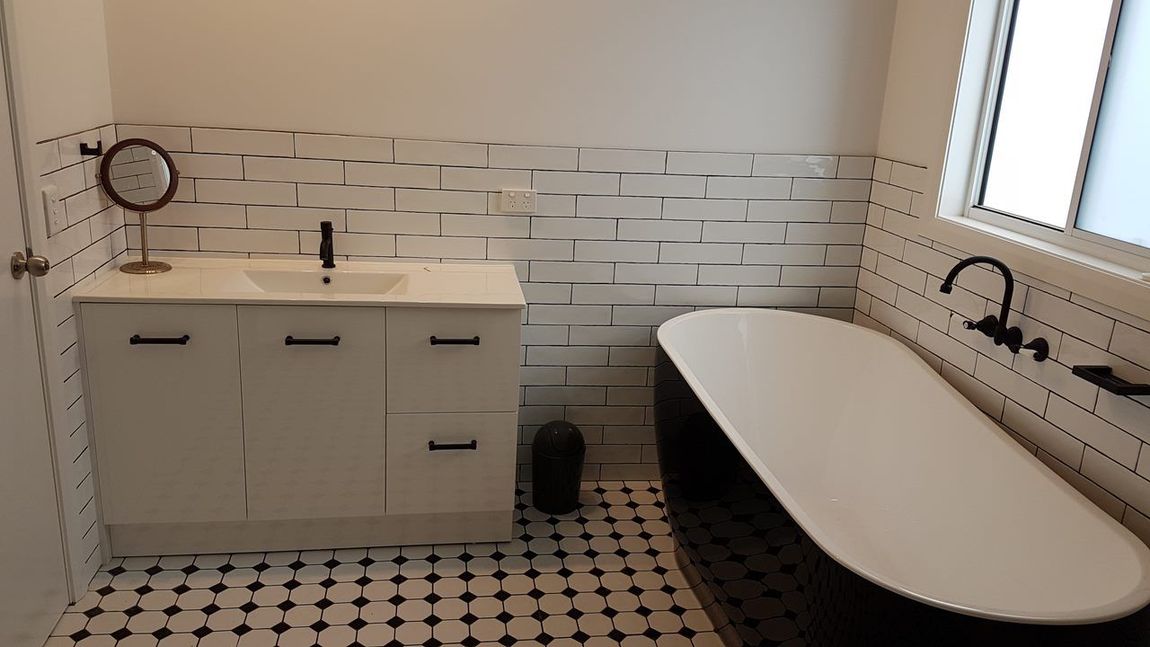 A Bathroom With A Bathtub, Sink And Mirror — Damn Fine Constructions In Bonville, NSW