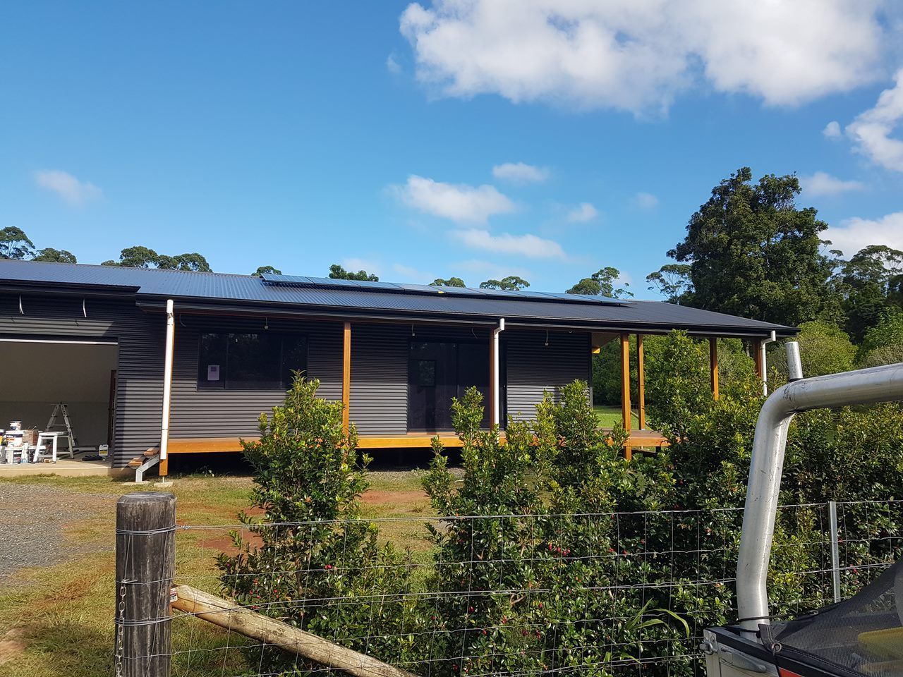 A Small House With A Red Door Is Surrounded By Flowers — Damn Fine Constructions In Bonville, NSW