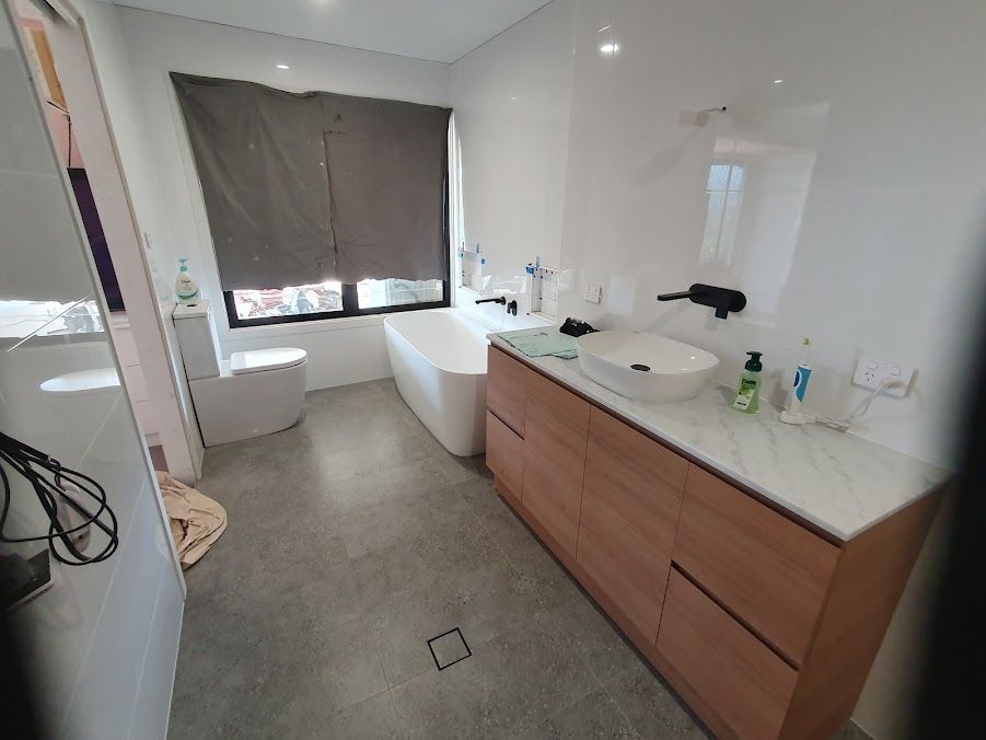 A Bathroom With A Tub, Sink, Toilet And Window — Damn Fine Constructions In Sawtell, NSW