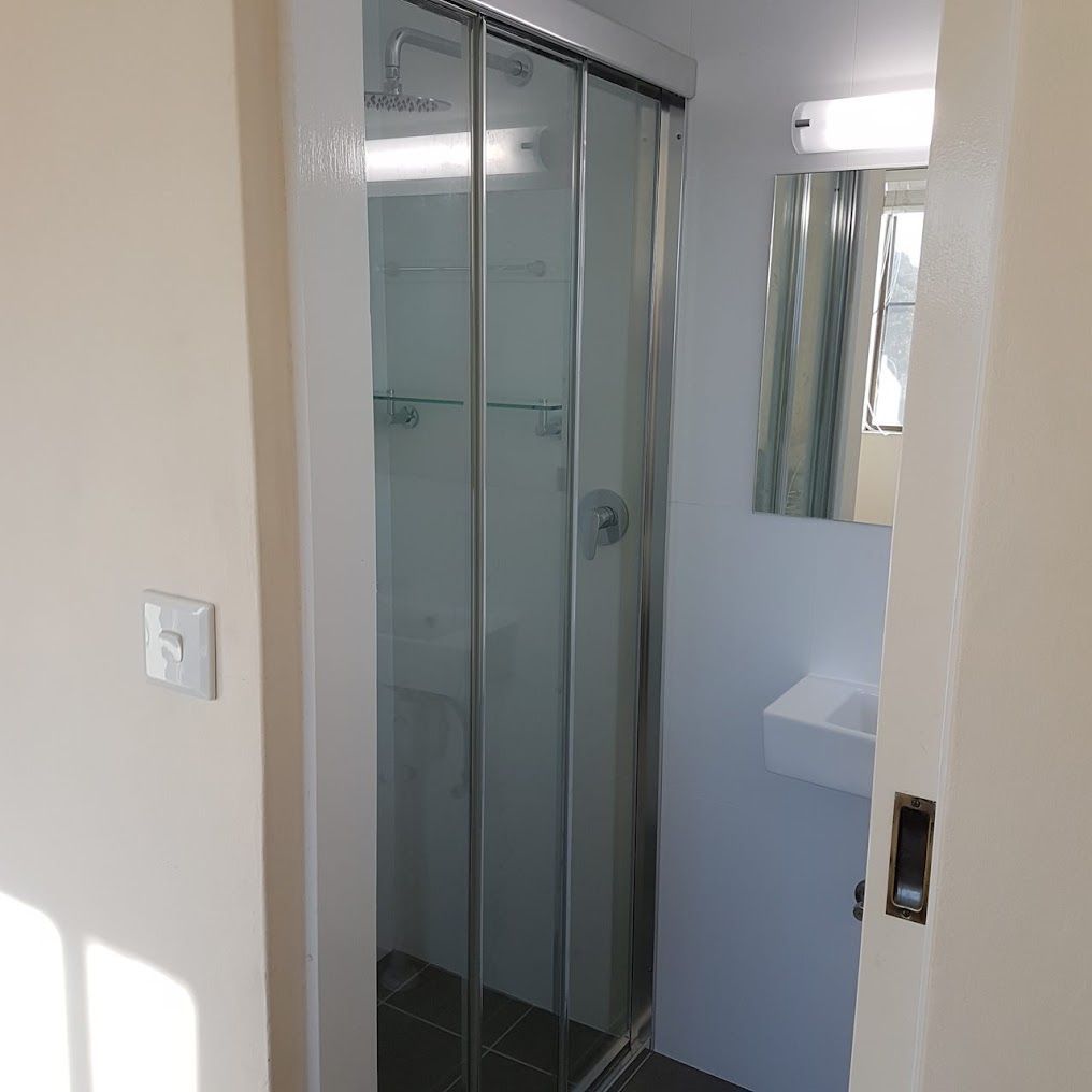 A Bathroom With A Sliding Glass Shower Door And A Sink — Damn Fine Constructions In Bonville, NSW