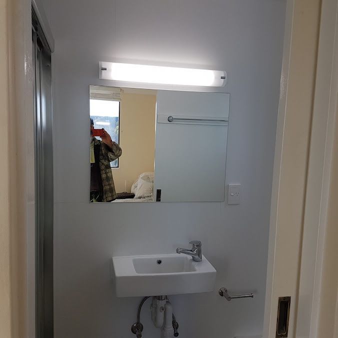 A Bathroom With A Sink, Mirror, And Light — Damn Fine Constructions In Sawtell, NSW