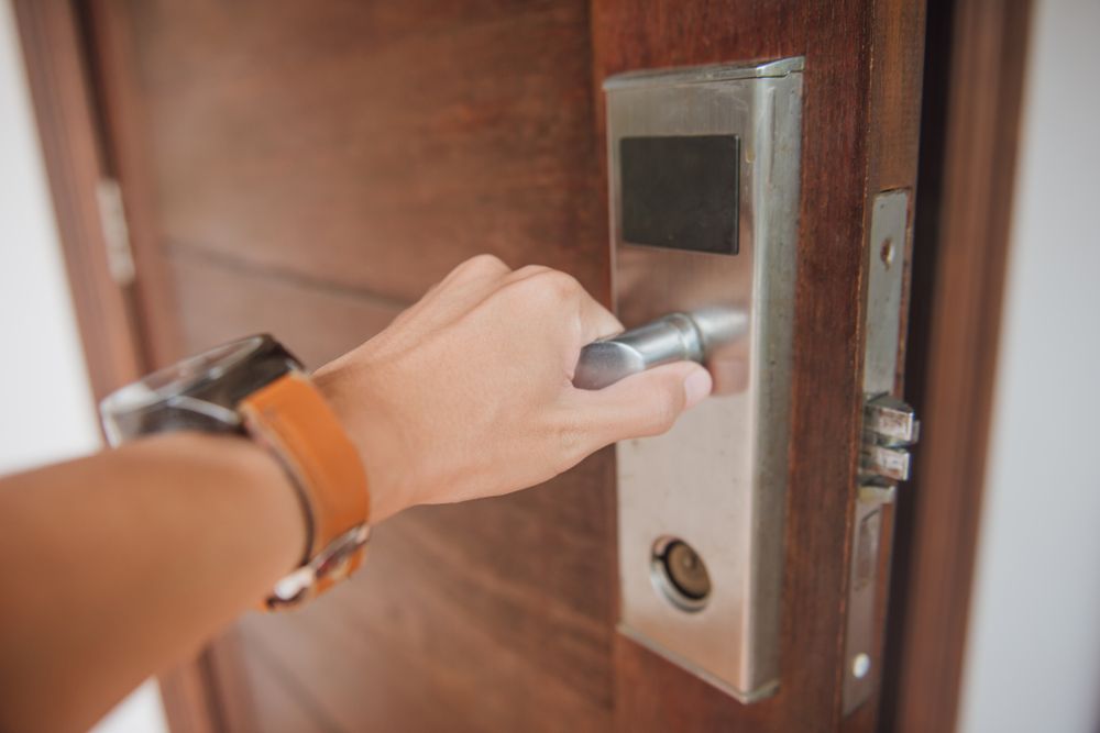 A Person Is Opening a Door with A Smart Lock — Southside Aluminium Windows and Doors in Yallah, NSW