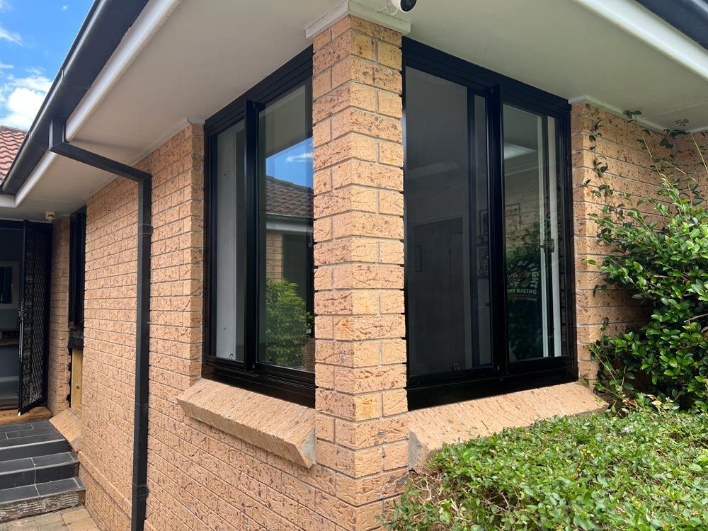 A Brick House with A Black Window on The Side of It — Southside Aluminium Windows and Doors in Yalla