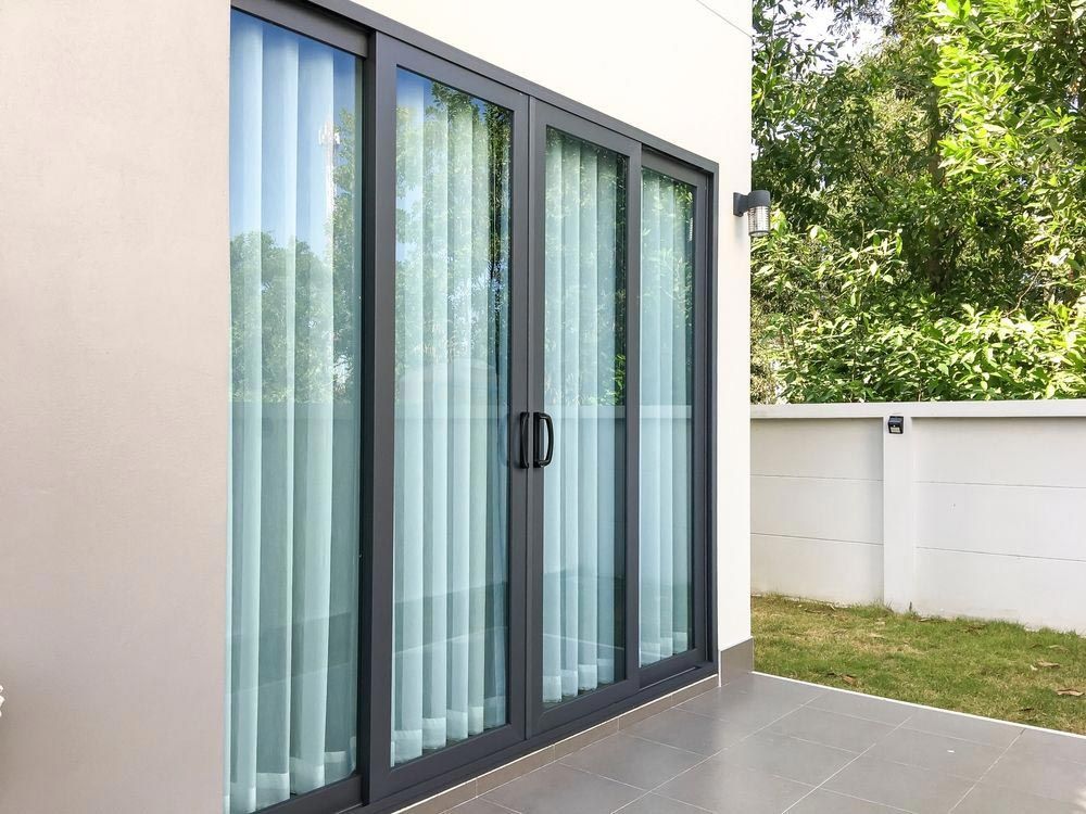 A Patio with Sliding Glass Doors and Curtains on A House — Southside Aluminium Windows and Doors in 