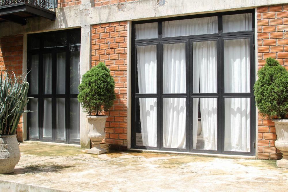 A Brick Building with A Lot of Windows and Potted Plants in Front of It — Southside Aluminium Window