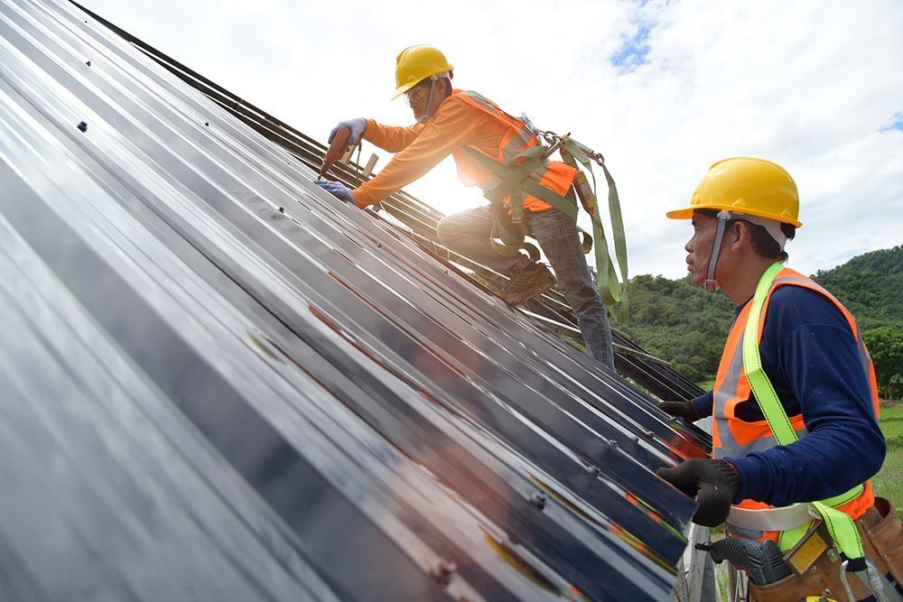 Two men in orange safety vests and helmets repairing a roof, representing G S Roofing Siding, trusted roofers Red Bank, NJ.