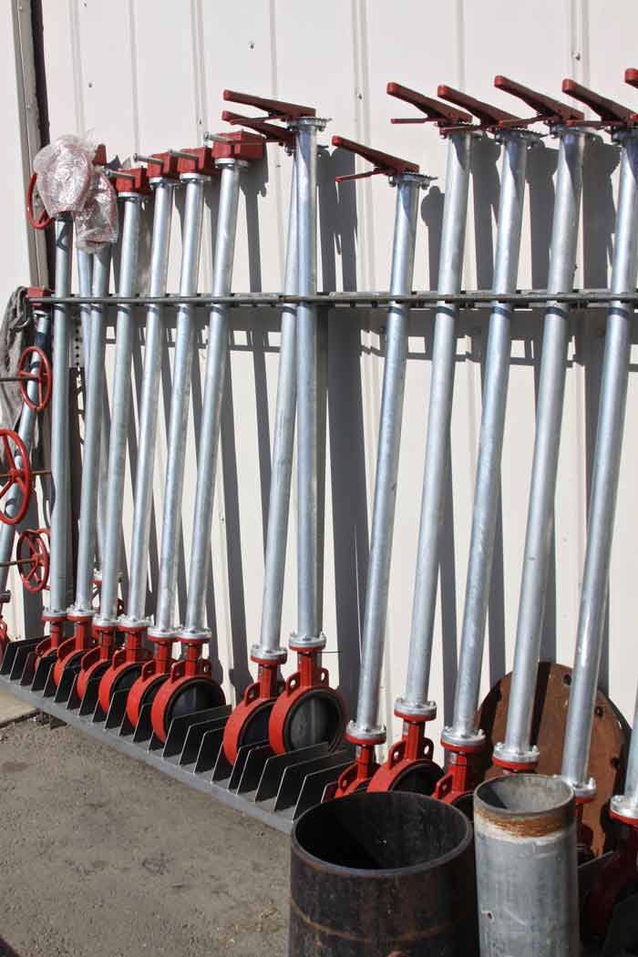 Row of red and silver industrial valves with long handles, lined up against a wall.
