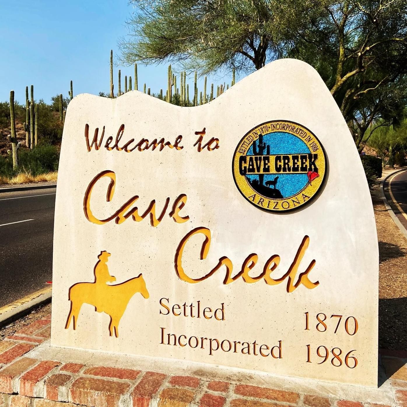Sign welcoming visitors to Cave Creek, Arizona. Includes town seal, silhouette of a rider, and the years 1870 and 1986.